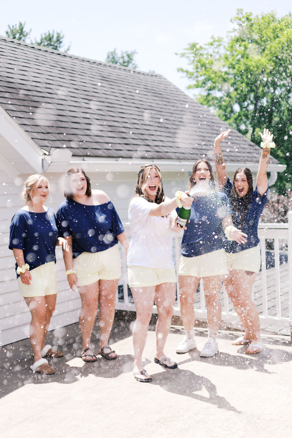 bride and bridesmaids with popped champagne