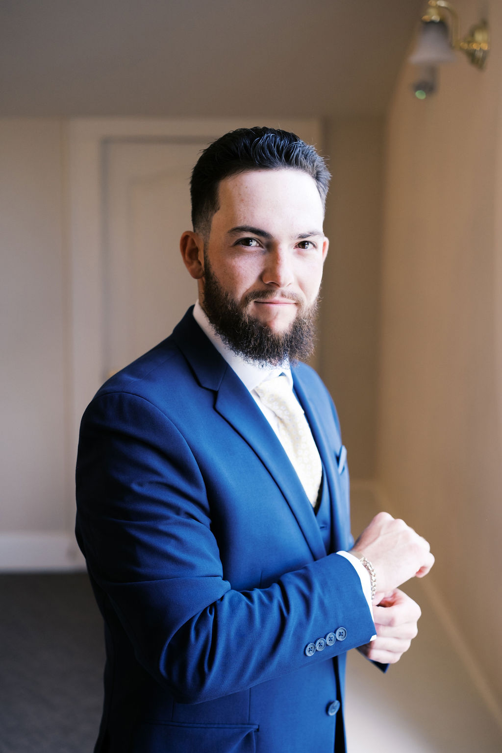 groom in blue suit adjusting his cufflinks