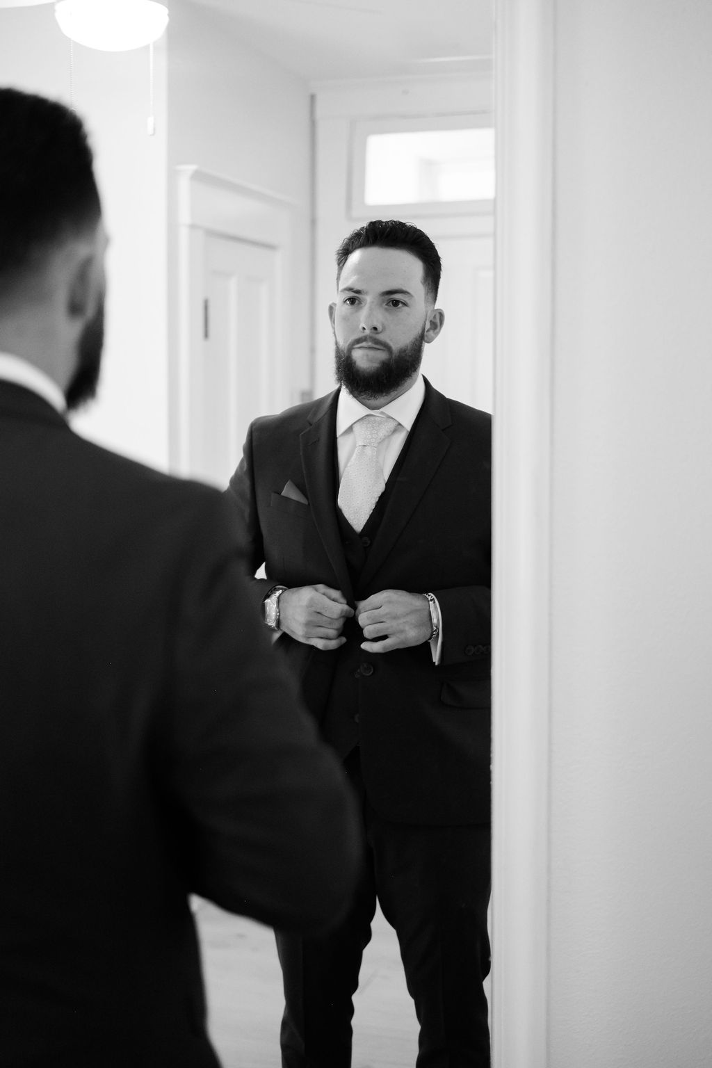 groom adjusting his suit in mirror