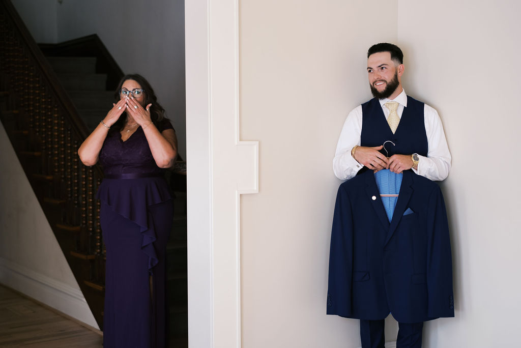 mother of the groom and groom waiting on opposite sides of a wall 