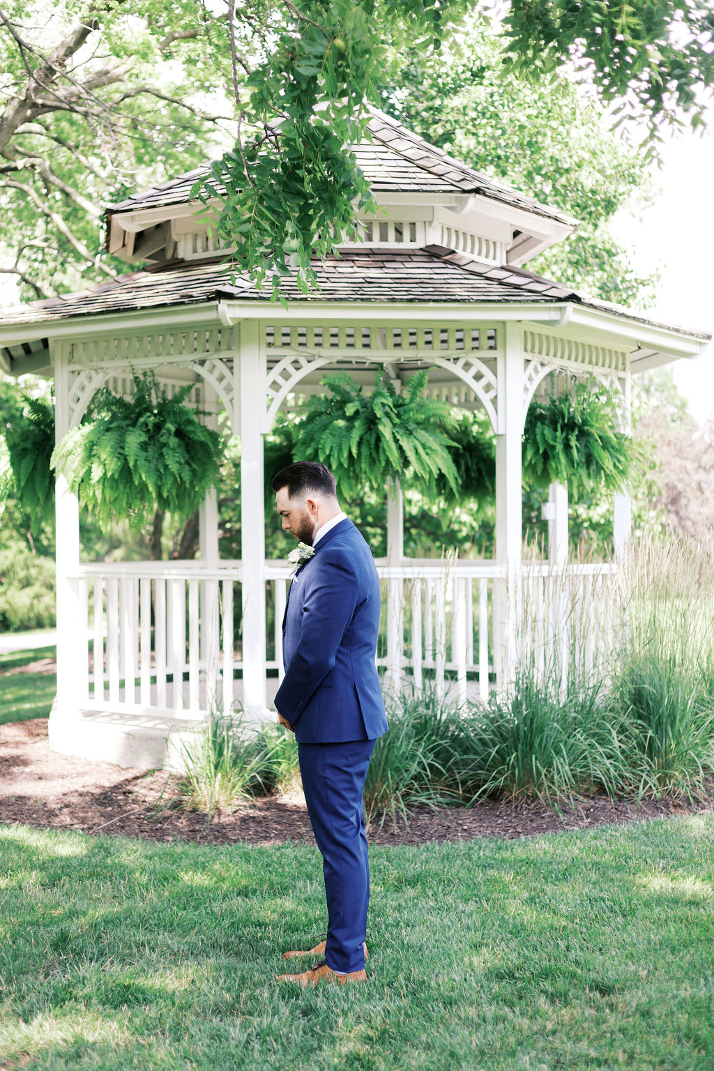 groom in a blue suit waiting in front of the gazebo at hawthorne house
