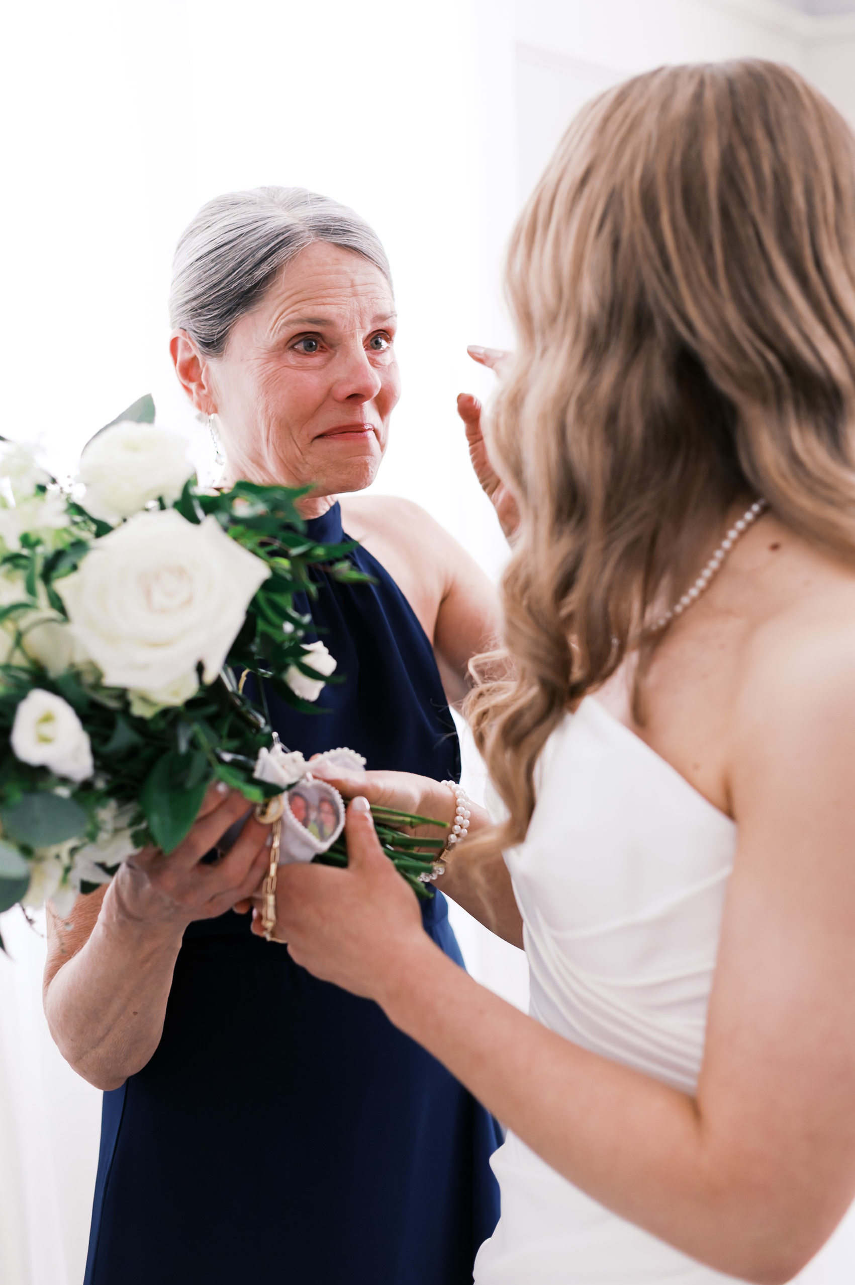 Bride and woman looking at each other with bouquet in their hands