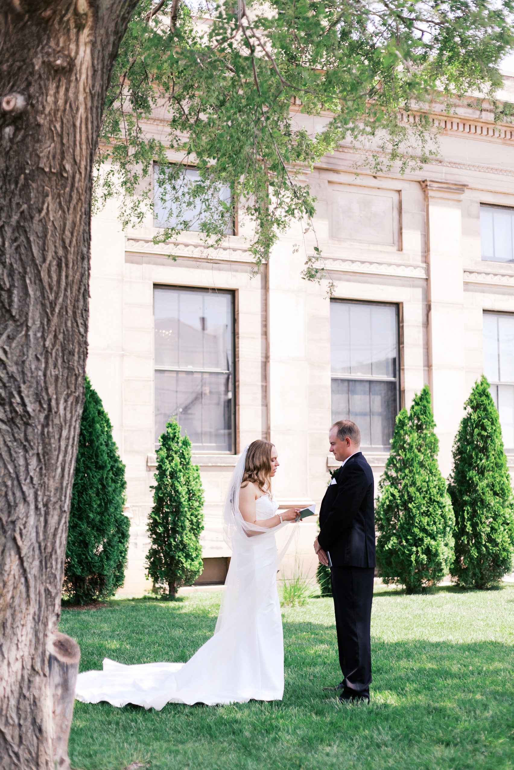 Couple reading vows to each other under a tree