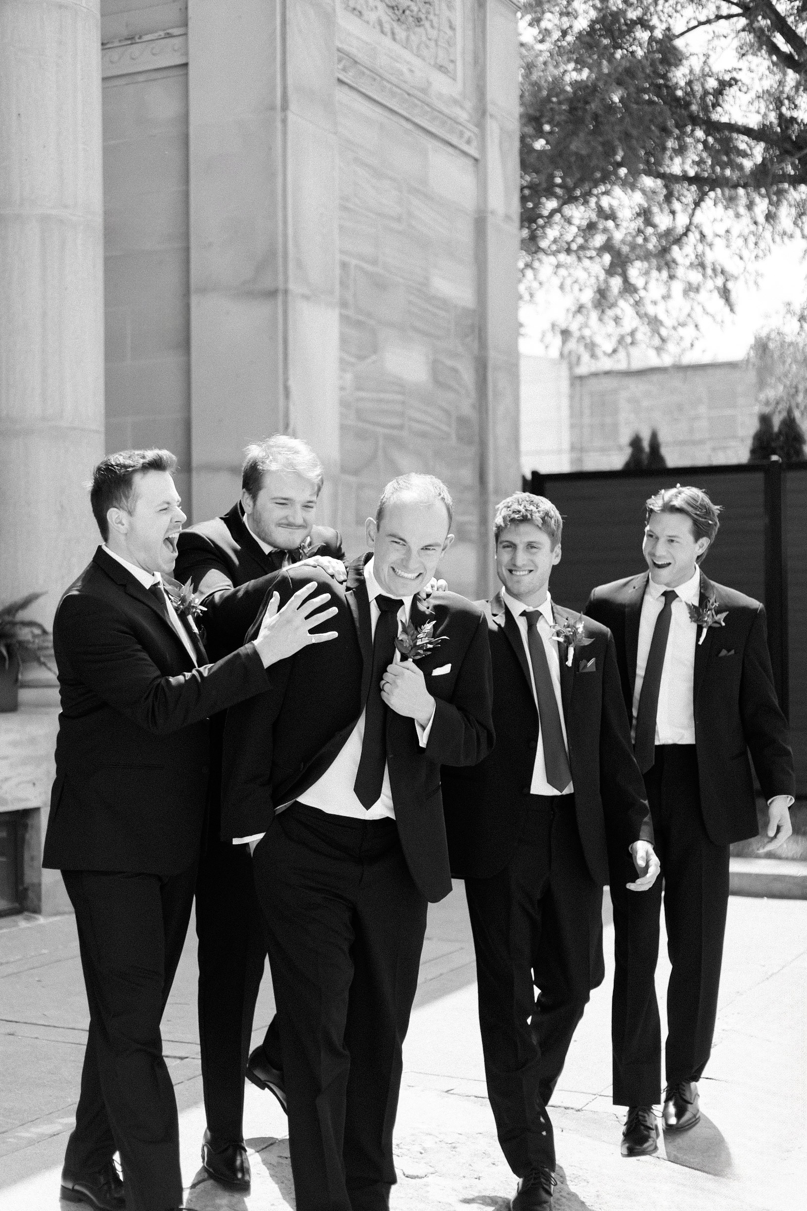 Groomsmen smiling and clapping groom on the back