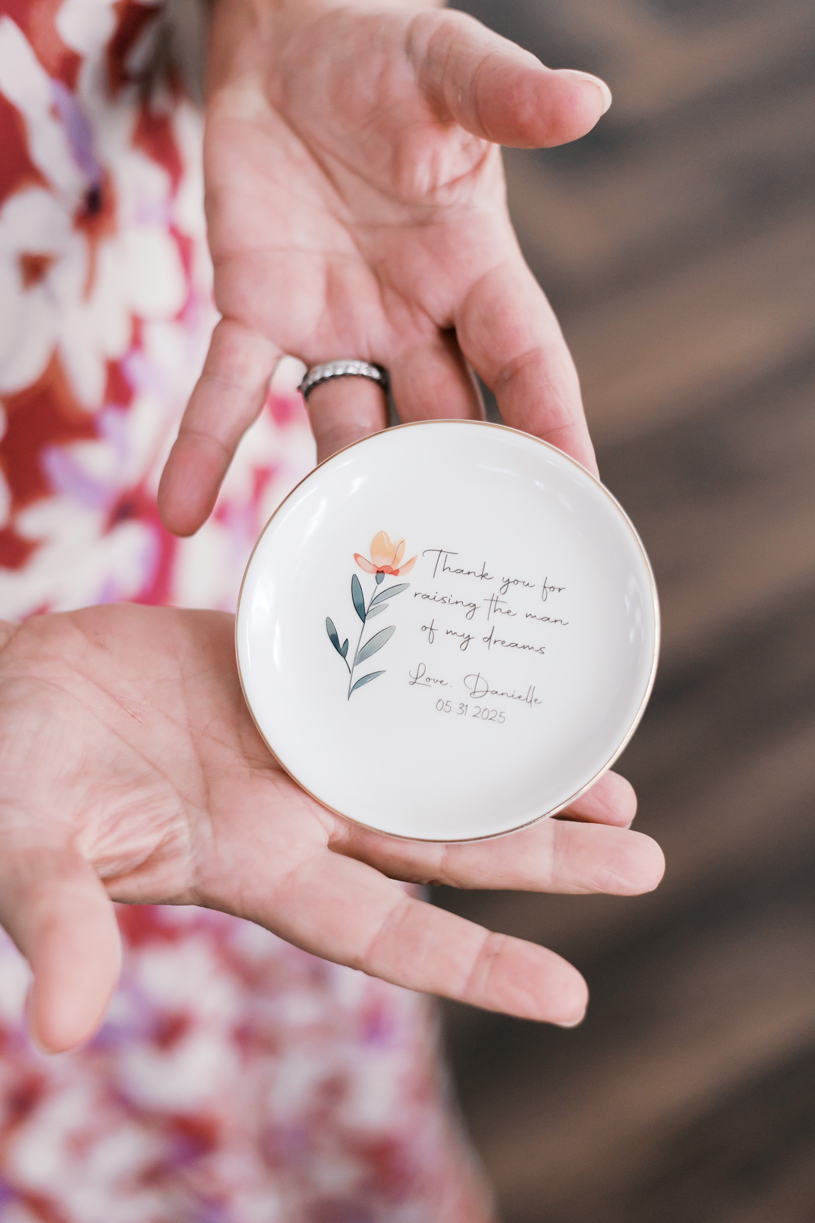 Up close photo of a woman holding a round dish with a flower and inscription "thank you for raising the man of my dreams"