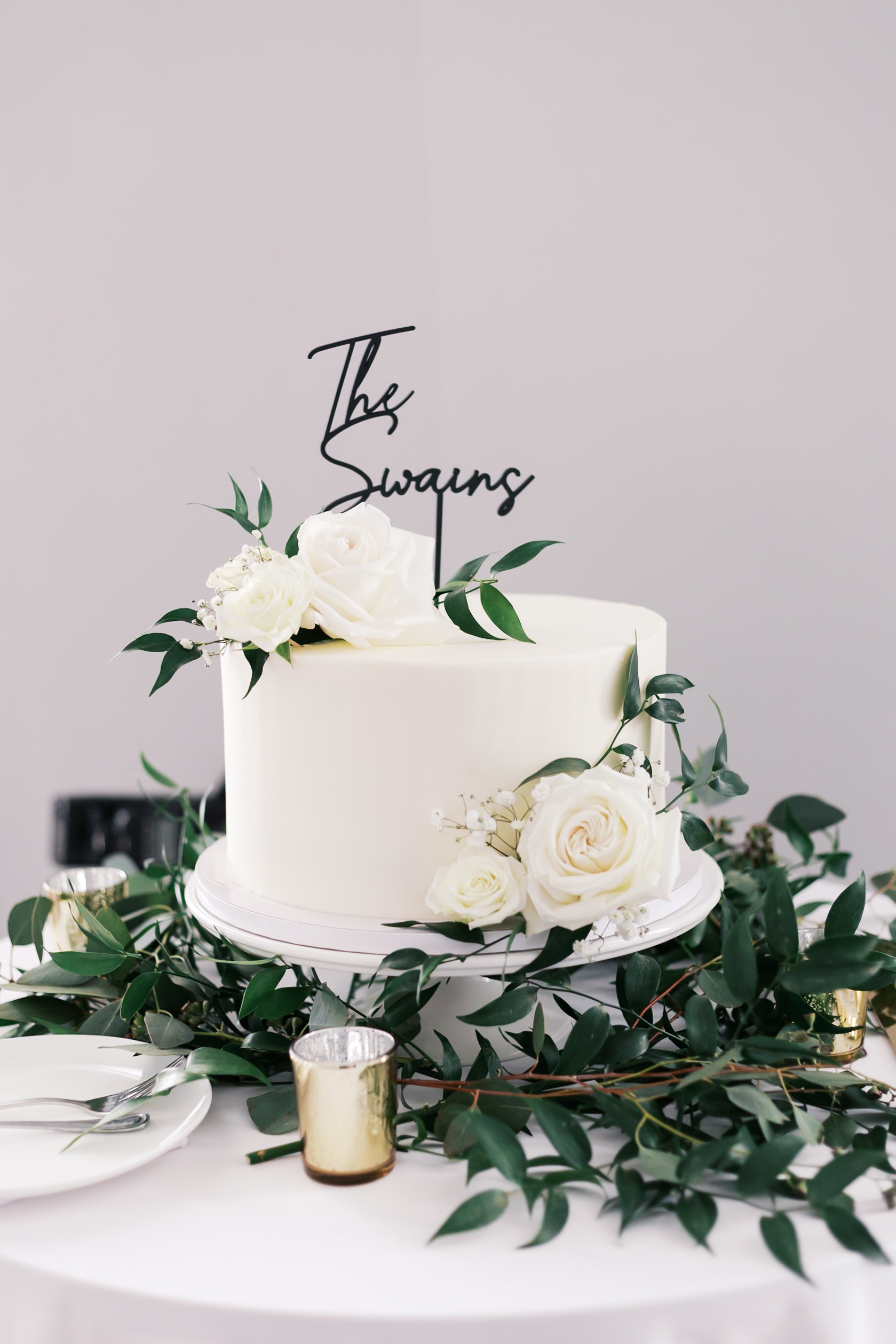 one tier white wedding cake with greenery and white roses
