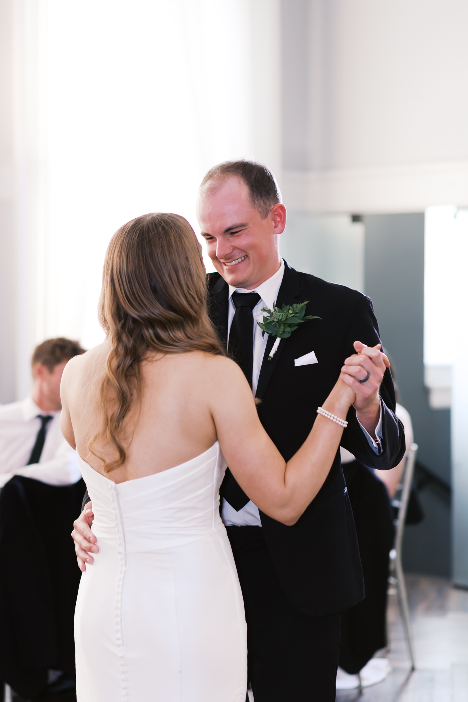 Groom looking down and smiling at bride as they dance