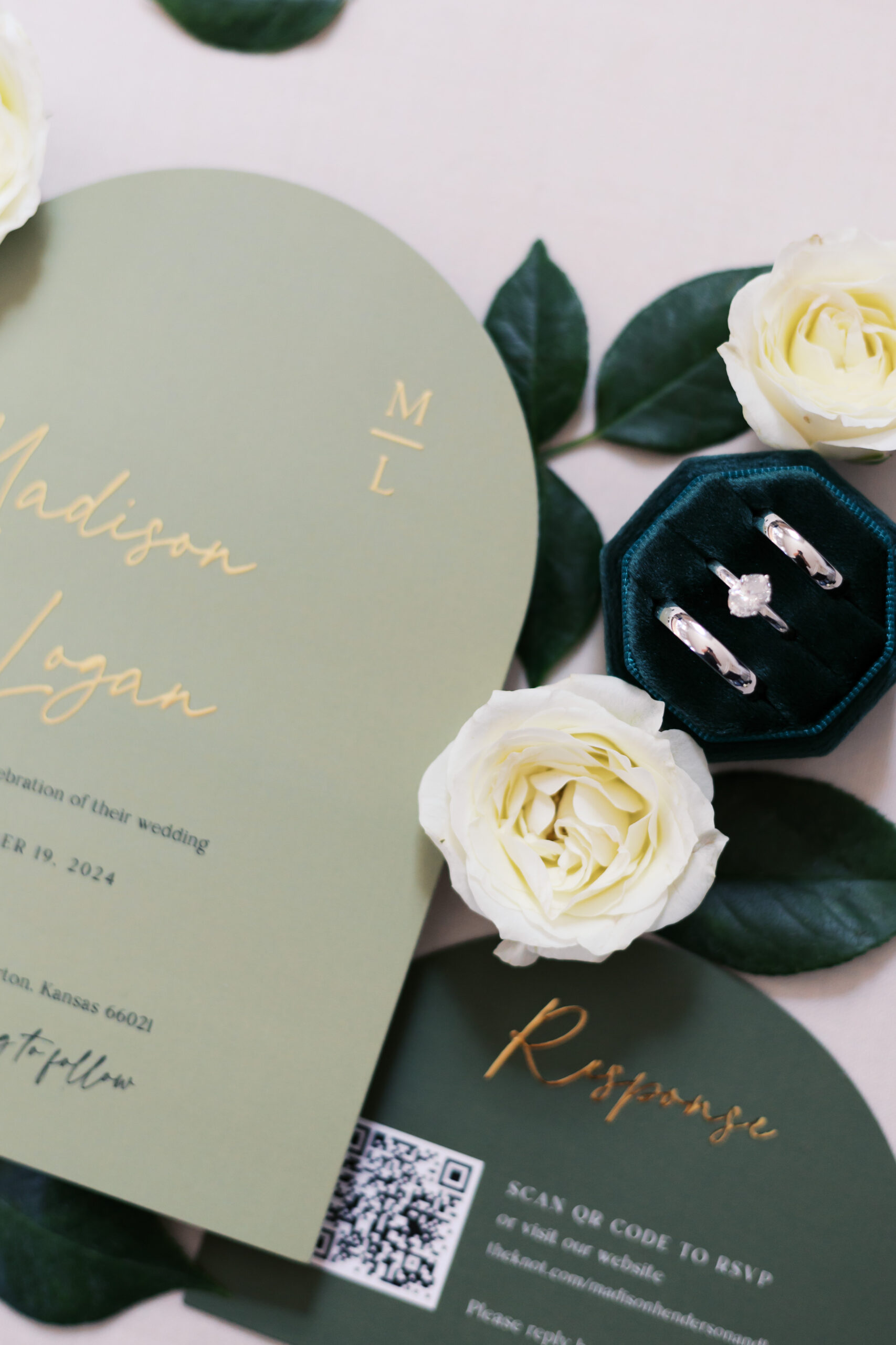 invitation and green ring box surrounded by greenery and white flowers