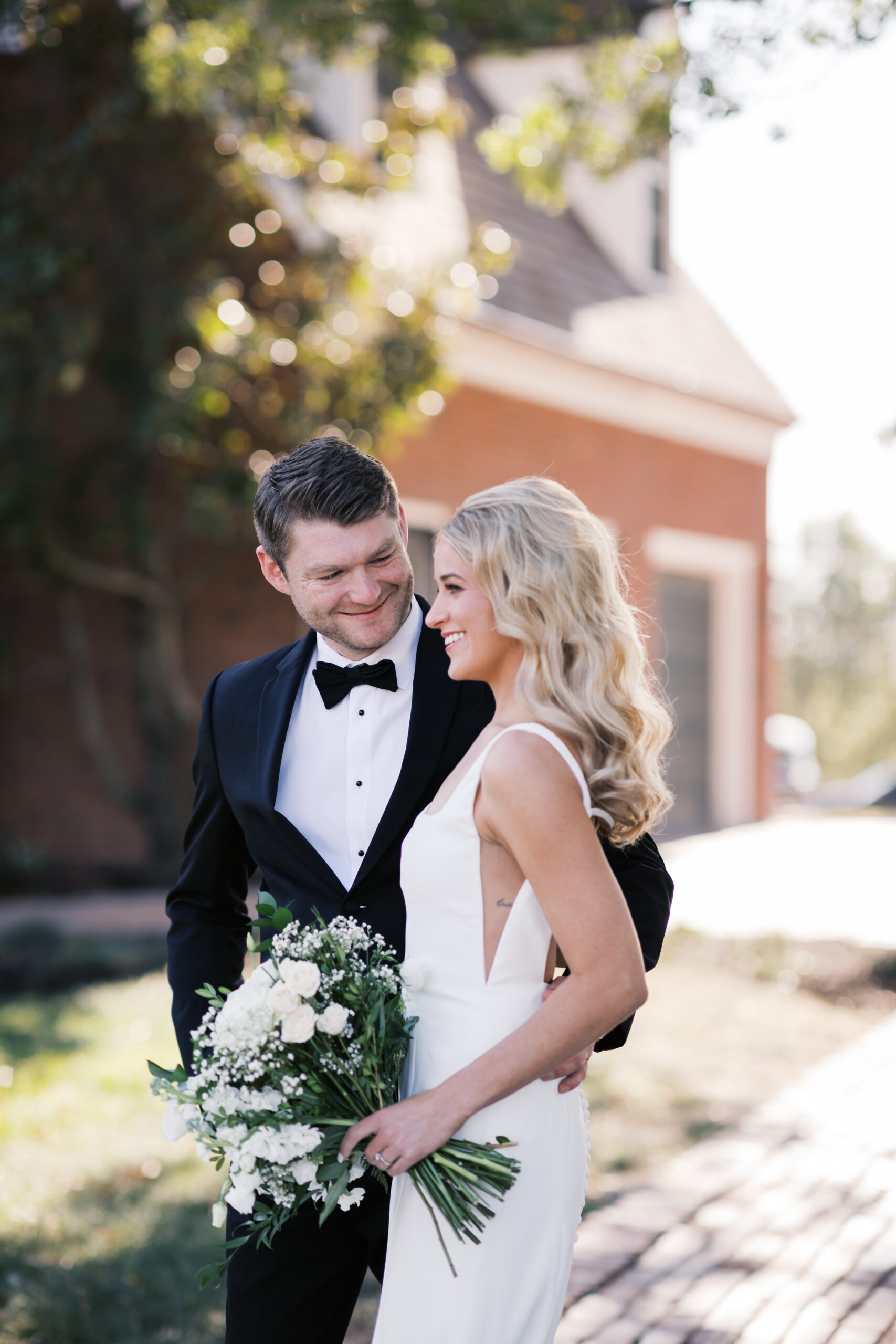 Bride and groom share a joyful moment outside Mildale Farm, smiling at each other as the bride holds a white bouquet.