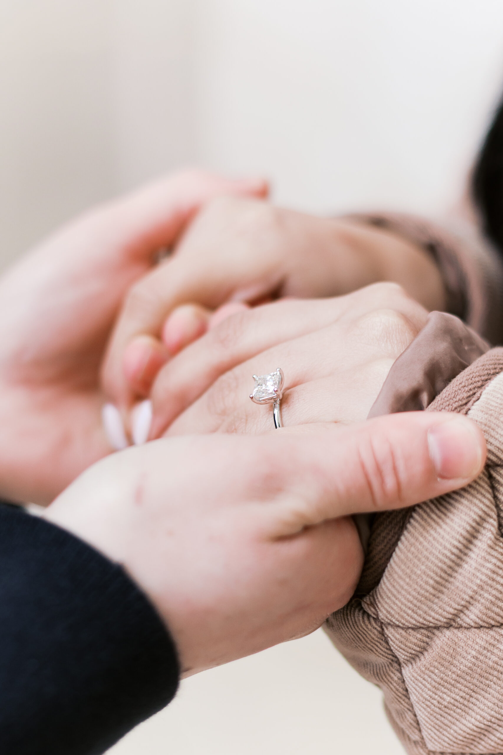 Close-up of an engagement ring on a person’s hand as their partner gently holds it during the proposal.