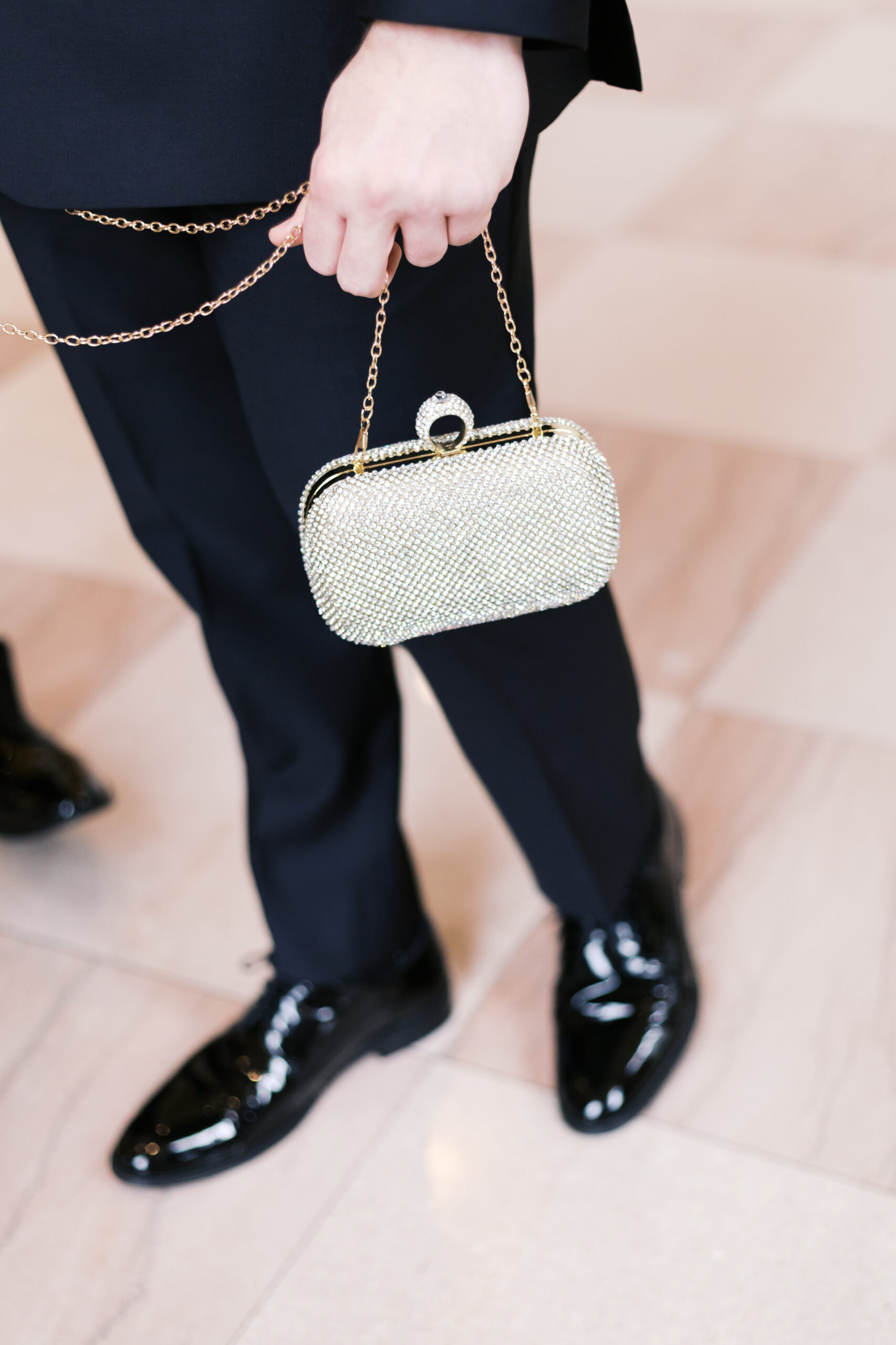 lose-up of a rhinestone-studded gold clutch held by the groom
