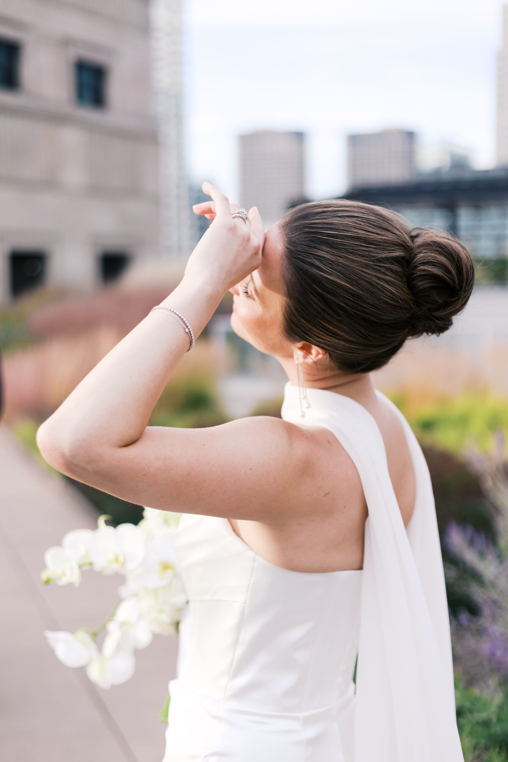 Bride striking a pose while holding her bouquet, standing on a rooftop garden in soft evening light.