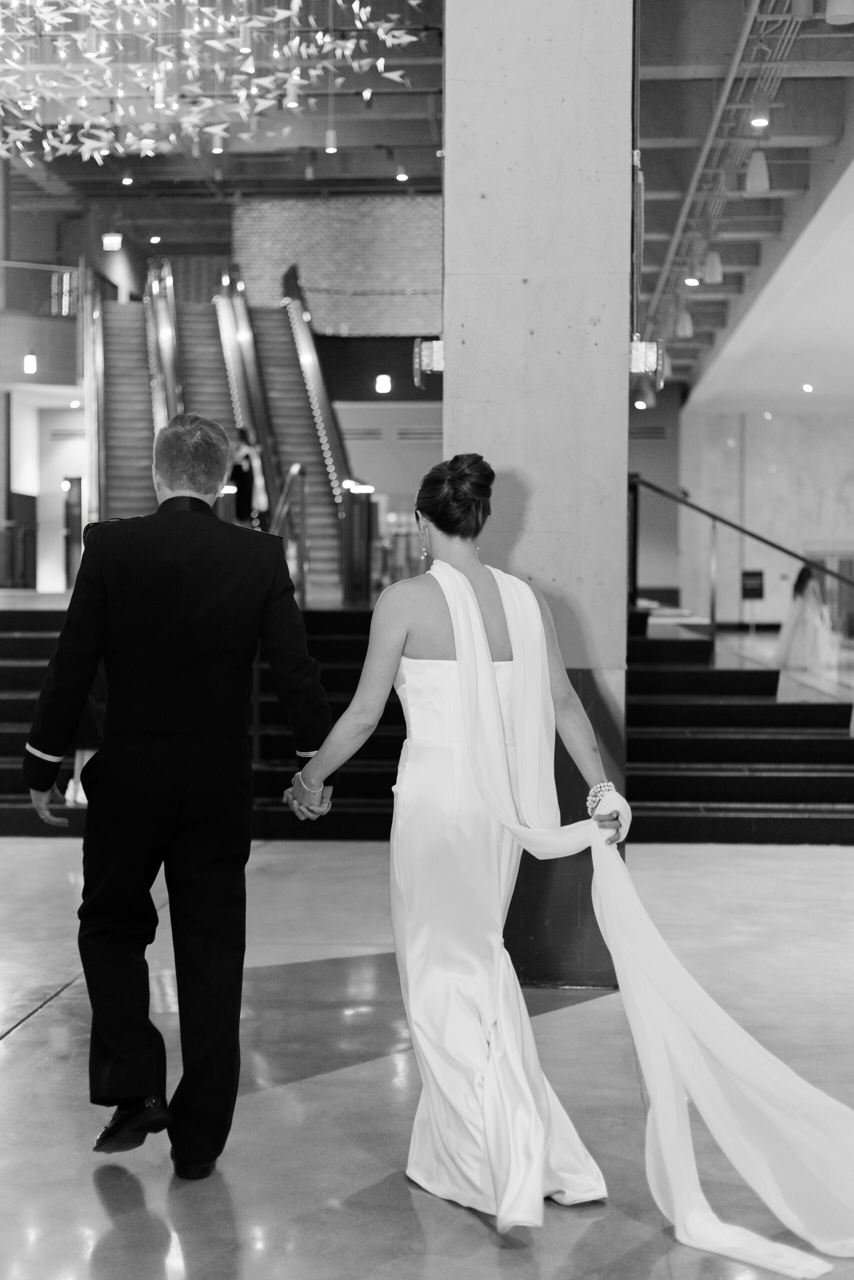 Black and white images of the bride and groom walking away hand in hand through the lobby of the Old Post Office Chicago