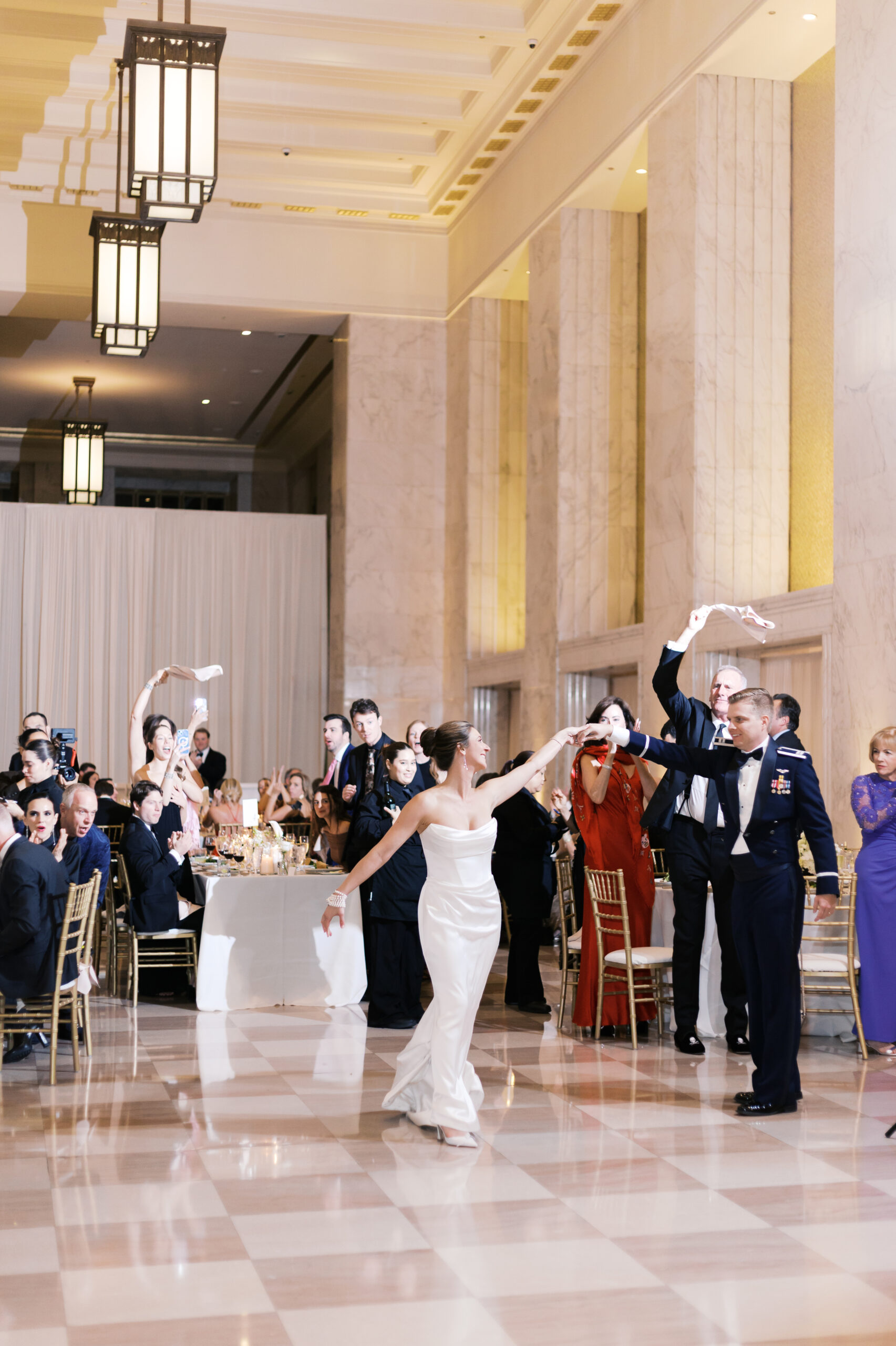 Bride and groom dancing as the crowd cheers and waves their napkins.