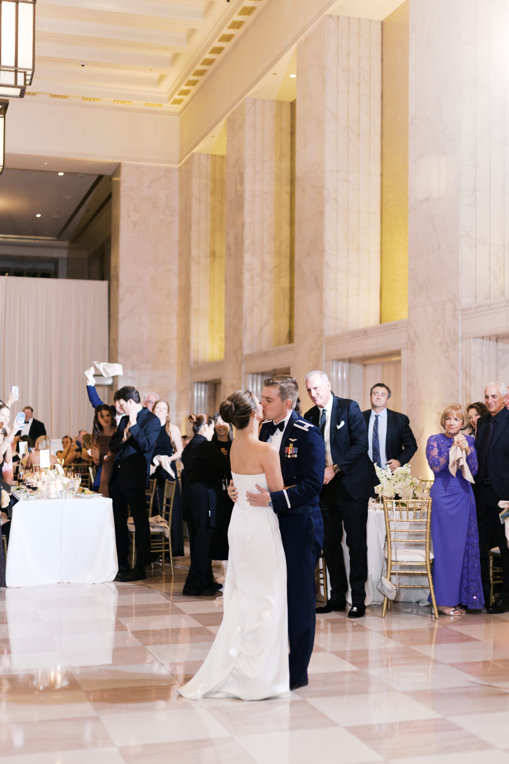 Bride and groom kiss while dancing during their first dance surrounded by guests