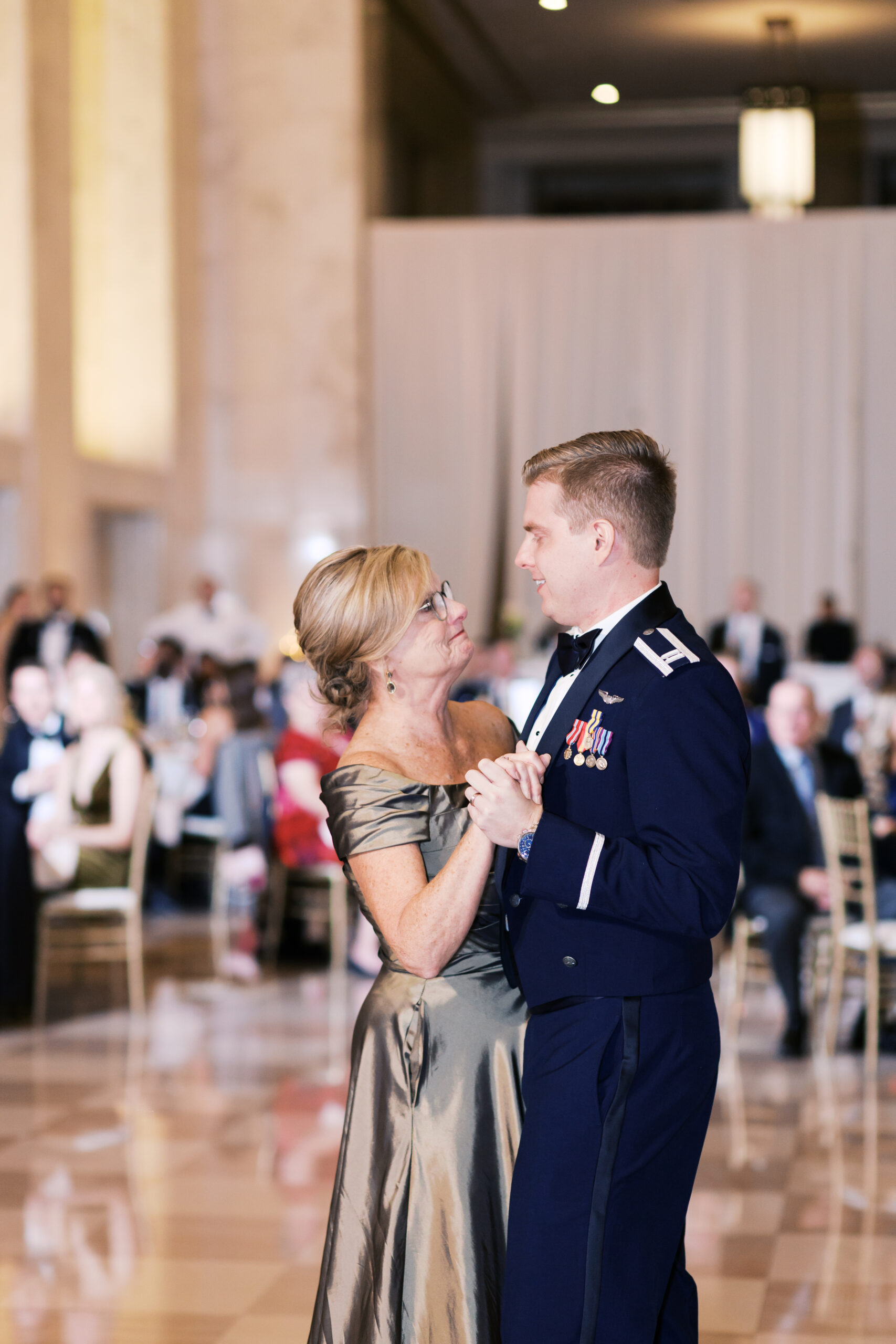 Groom in military dress dancing with his mother at the wedding reception.