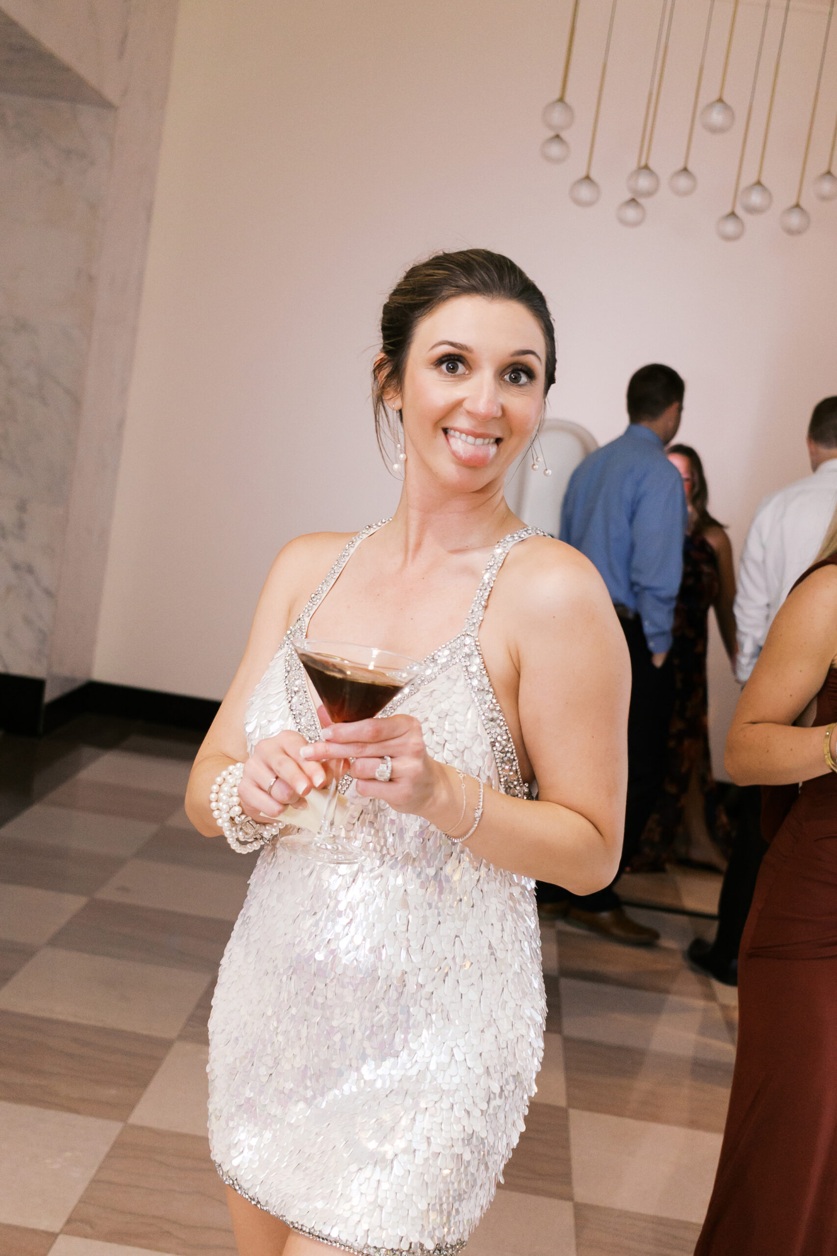 Bride holding an espresso martini while sticking out her tongue