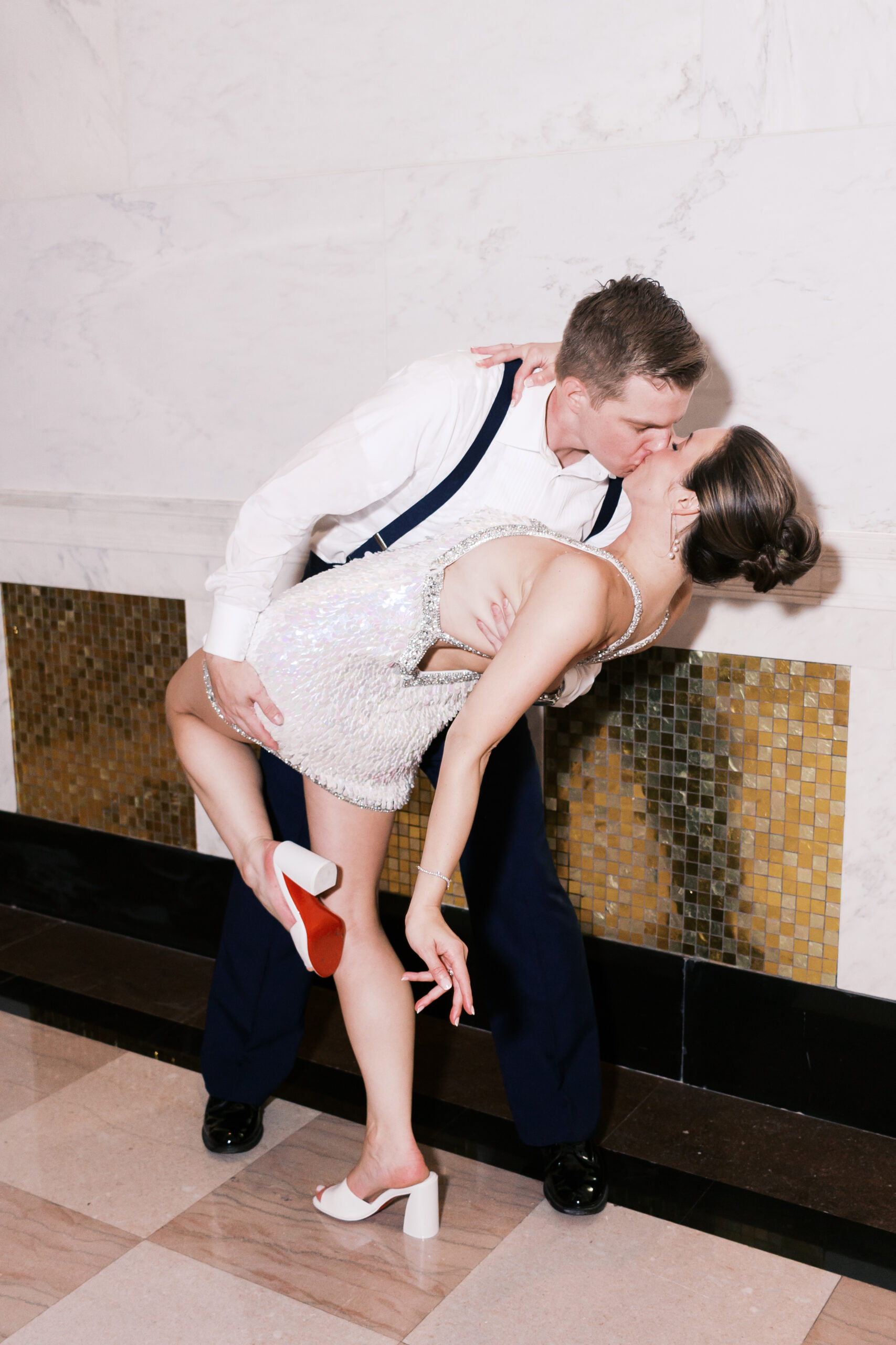 The groom dips the bride and kisses her as she raises one leg.