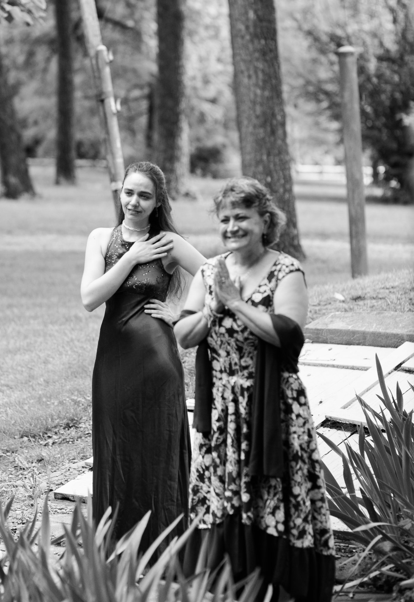 Black and white photo of two women standing outdoors, visibly moved as they see the bride for the first time.