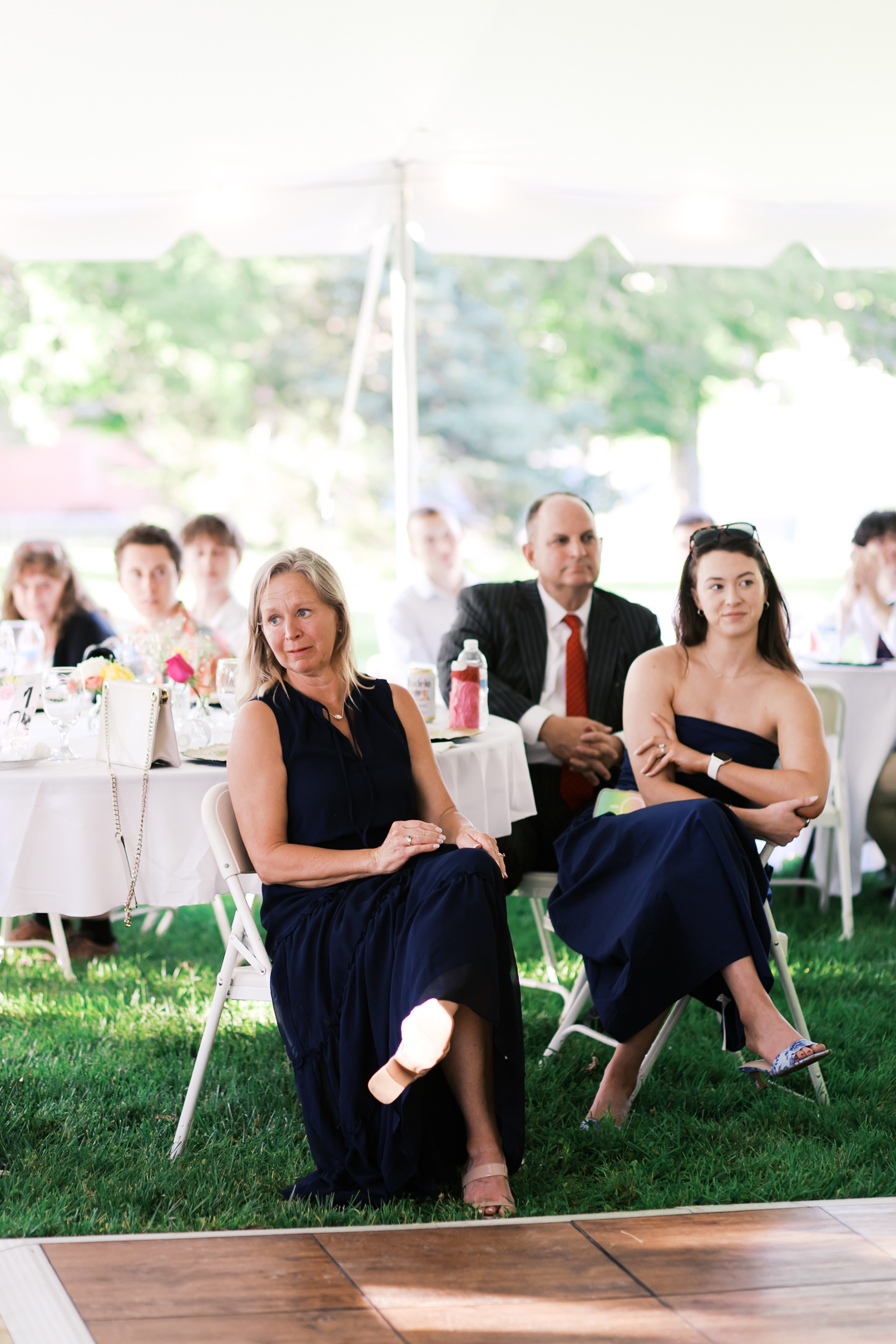 Two women in dark dresses sitting at a wedding reception.