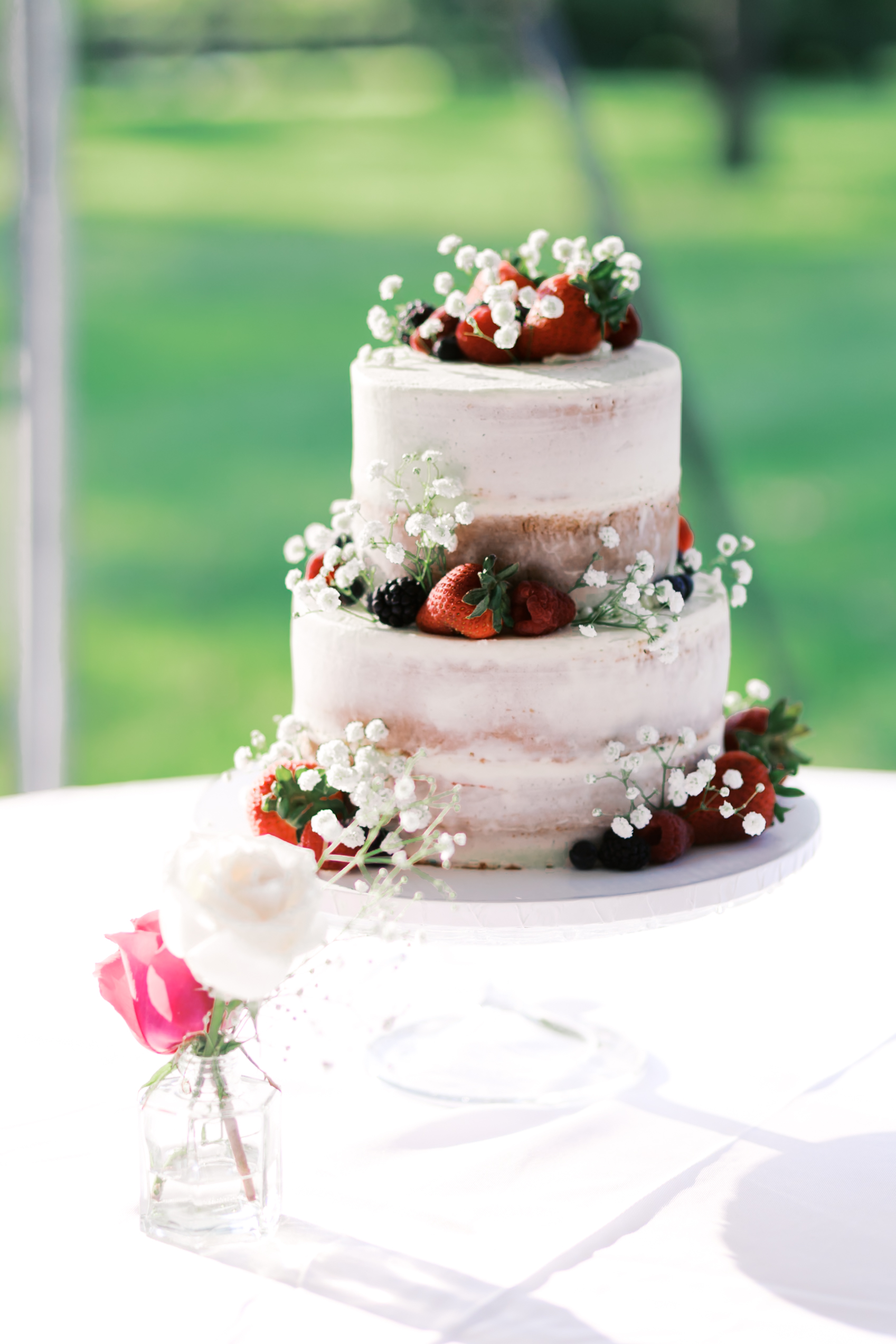 White two tiered cake covered with strawberries, blackberries and baby's breath.