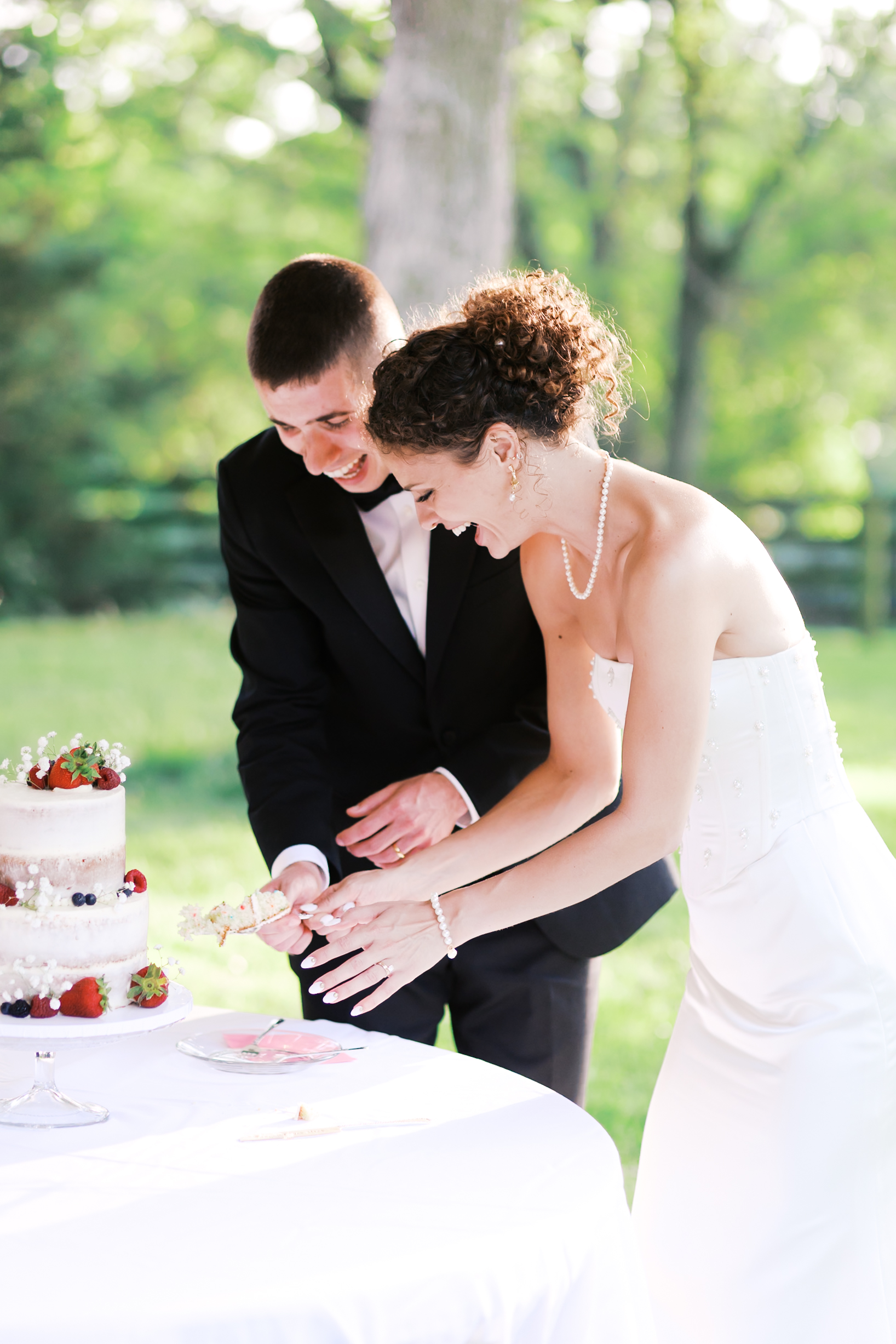 Bride and groom laughing as they serve a piece of their wedding cake.