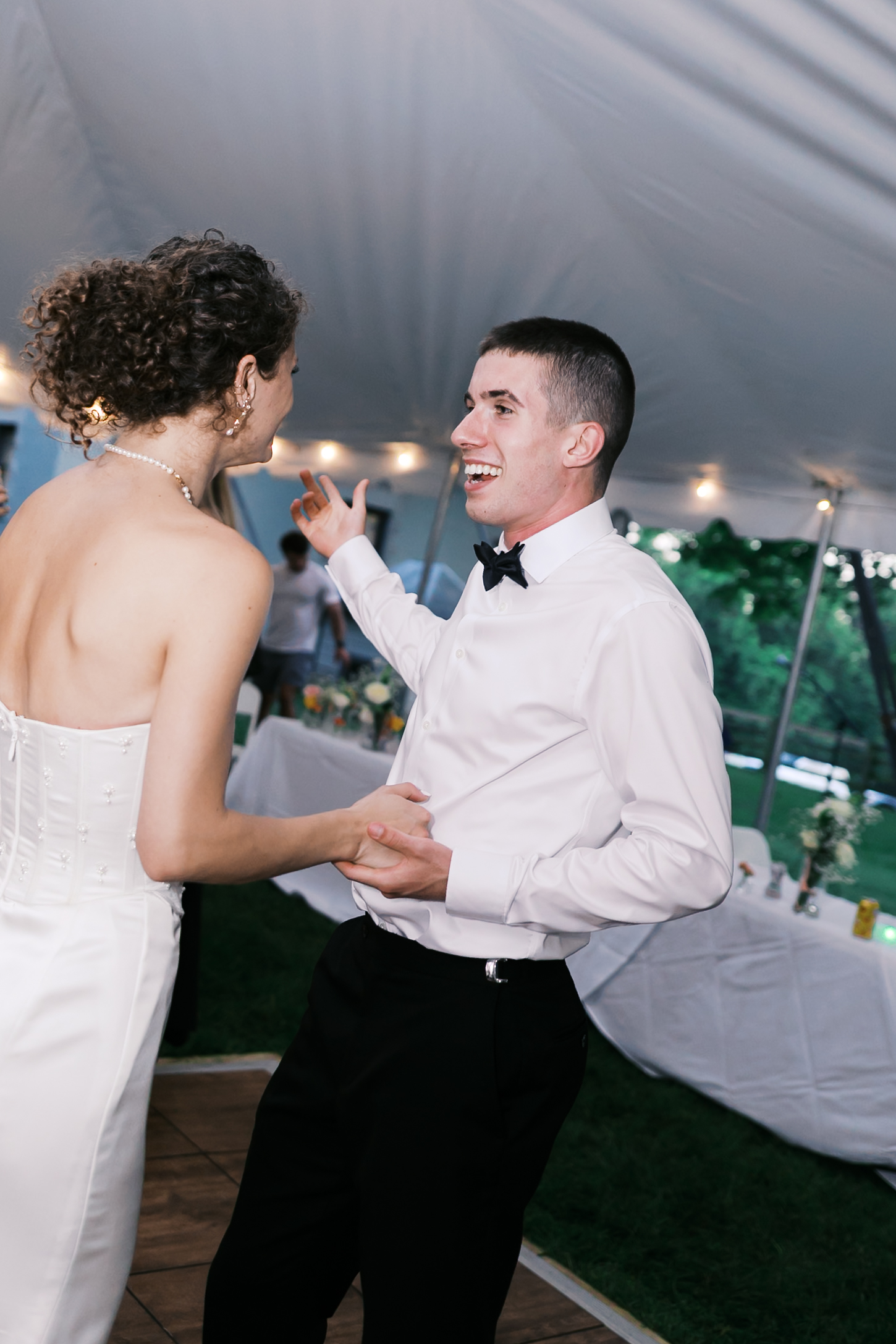 Groom smiling at bride as he gestures to something in the distance.