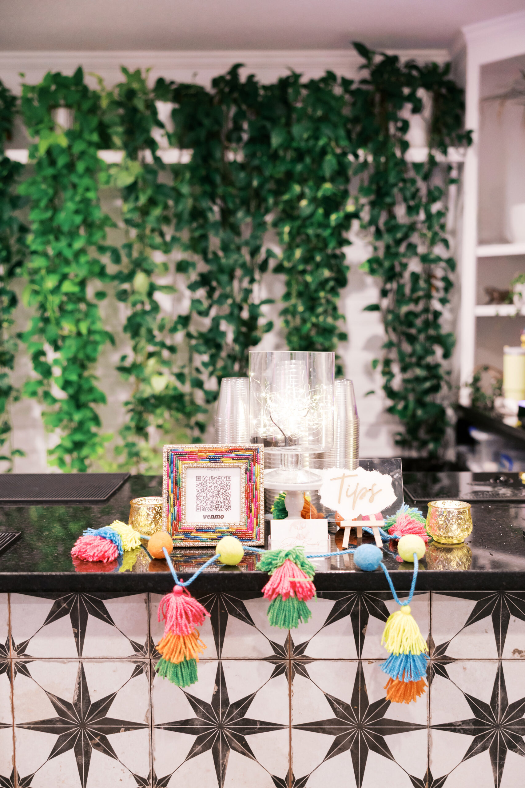 Colorful Jaggo wedding tips station with Venmo QR code, tassel garland, and candle decor.
