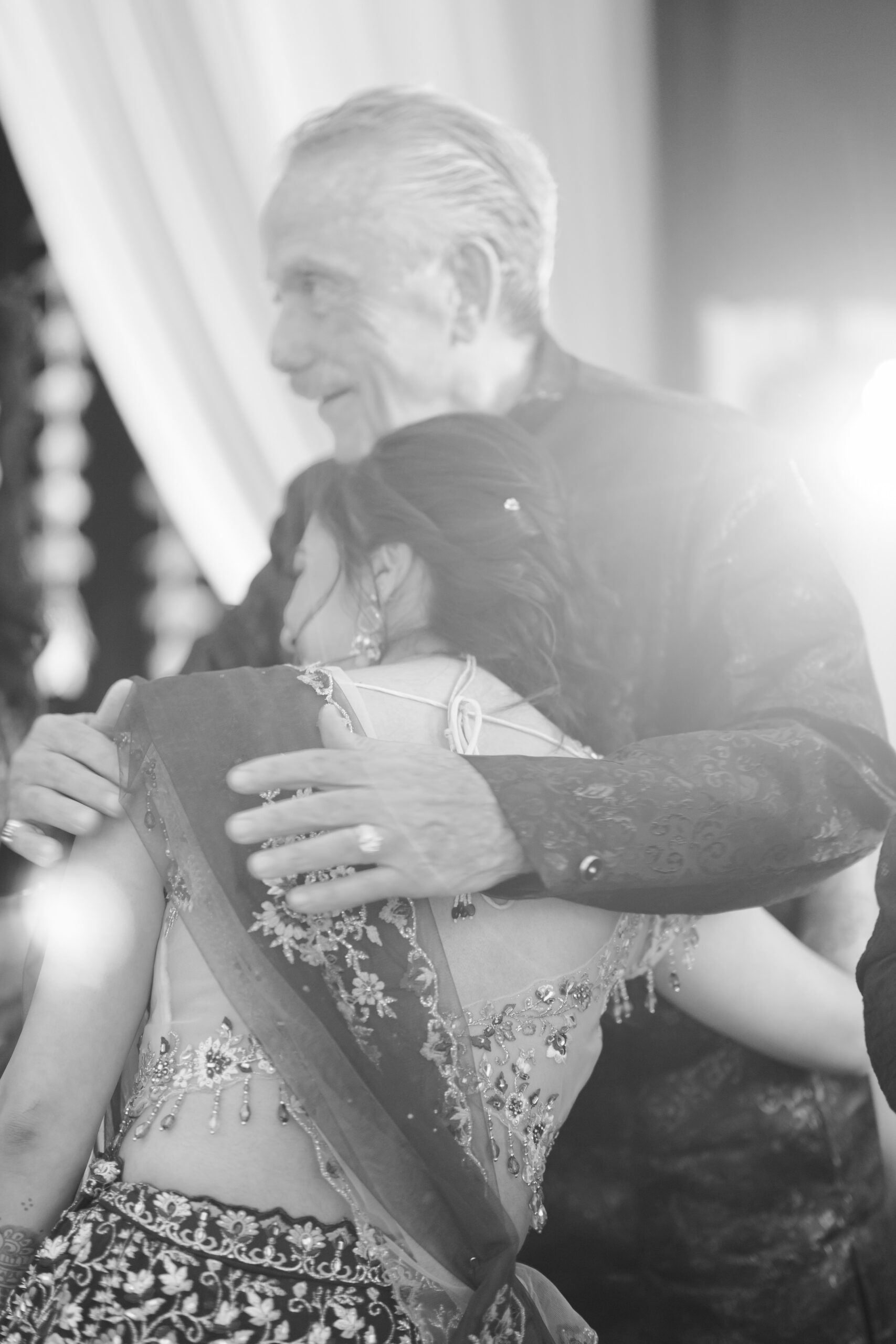 Emotional embrace between father and daughter at South Asian wedding event.