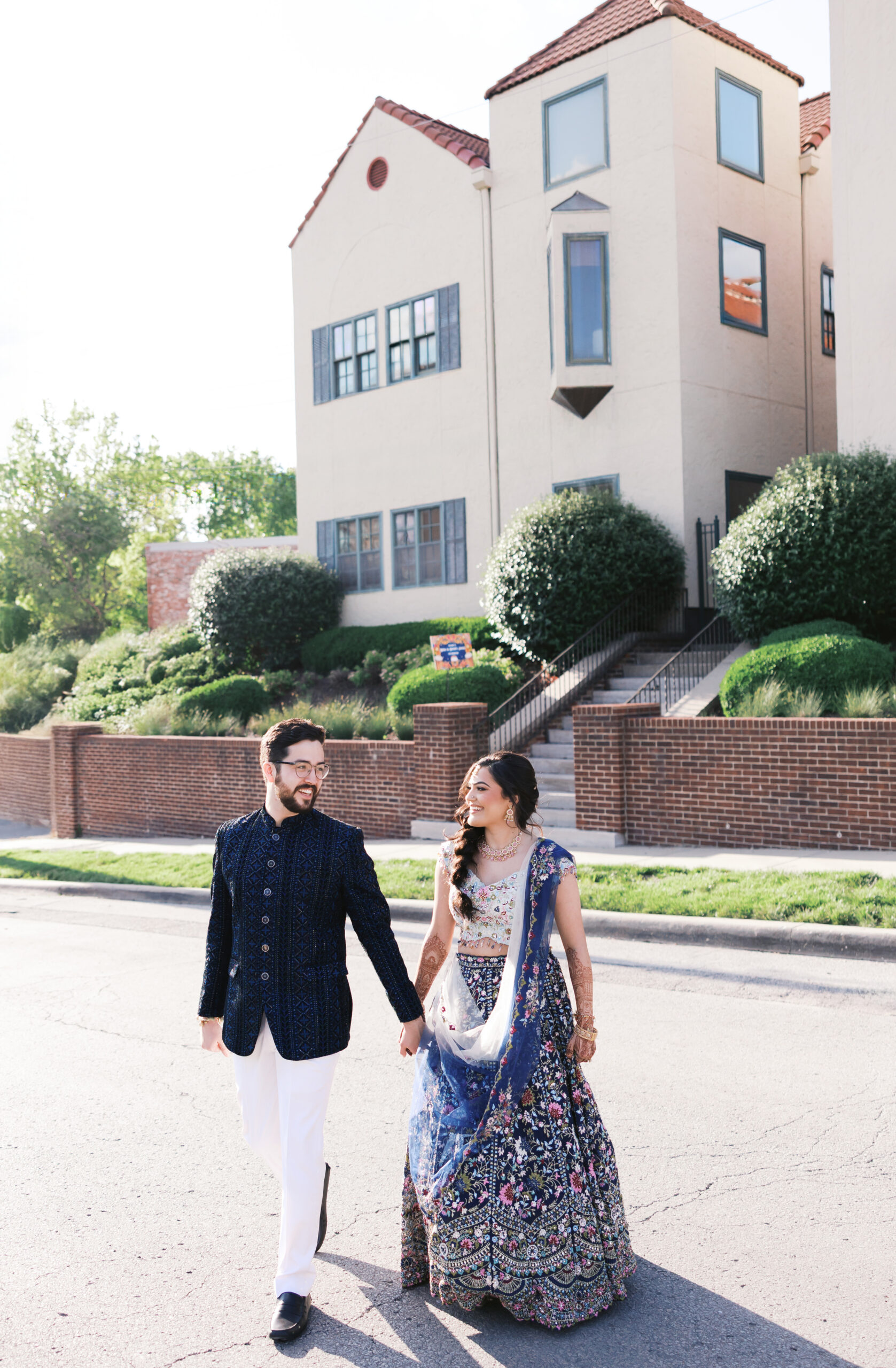 Couple holding hands outside Spanish-style wedding venue.