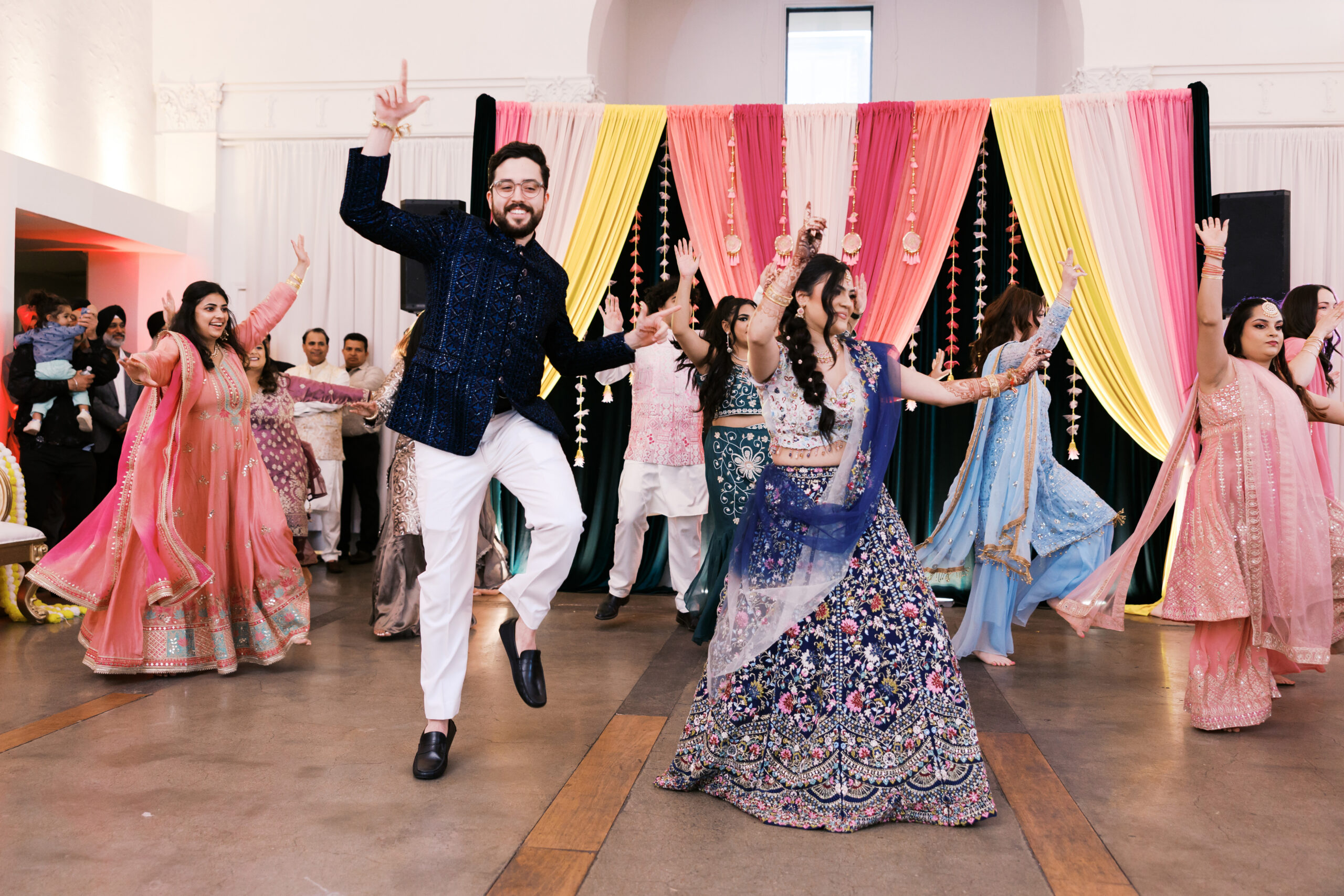Bride and groom leading group dance at vibrant Jaggo reception.