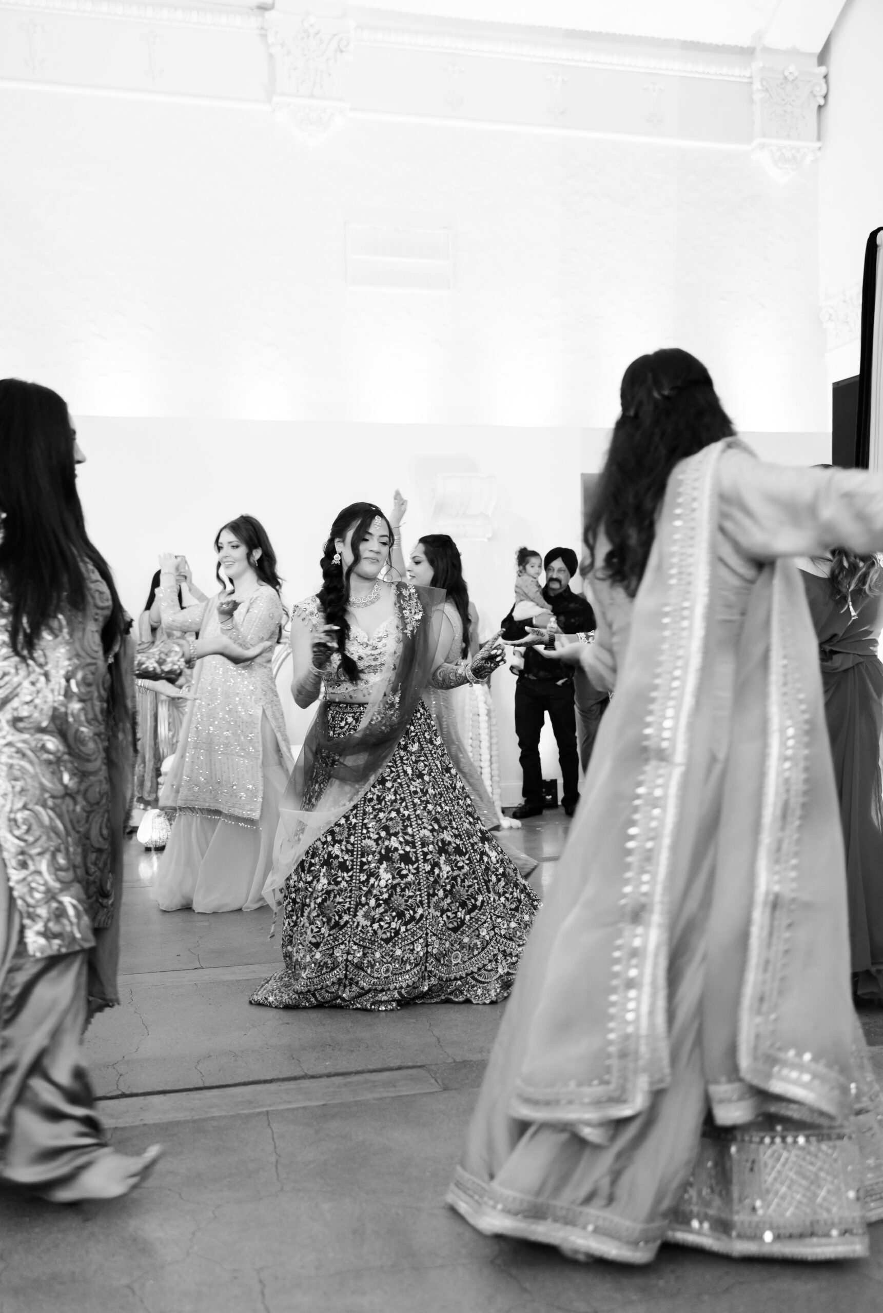 Bride dancing with guests during indoor Indian wedding celebration