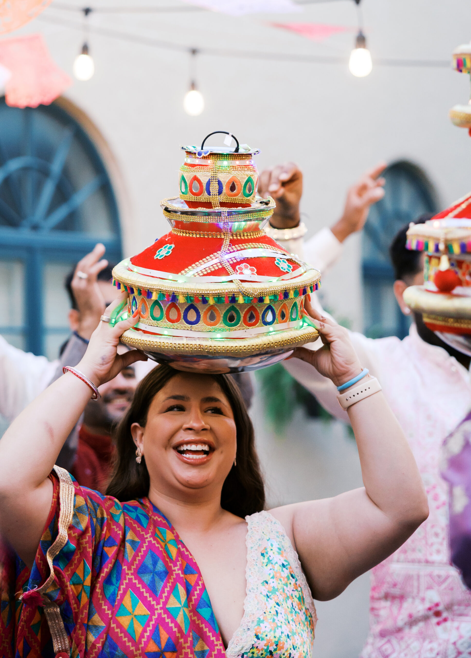 Guest balancing colorful decorated pot on her head during Jaggo ceremony.
