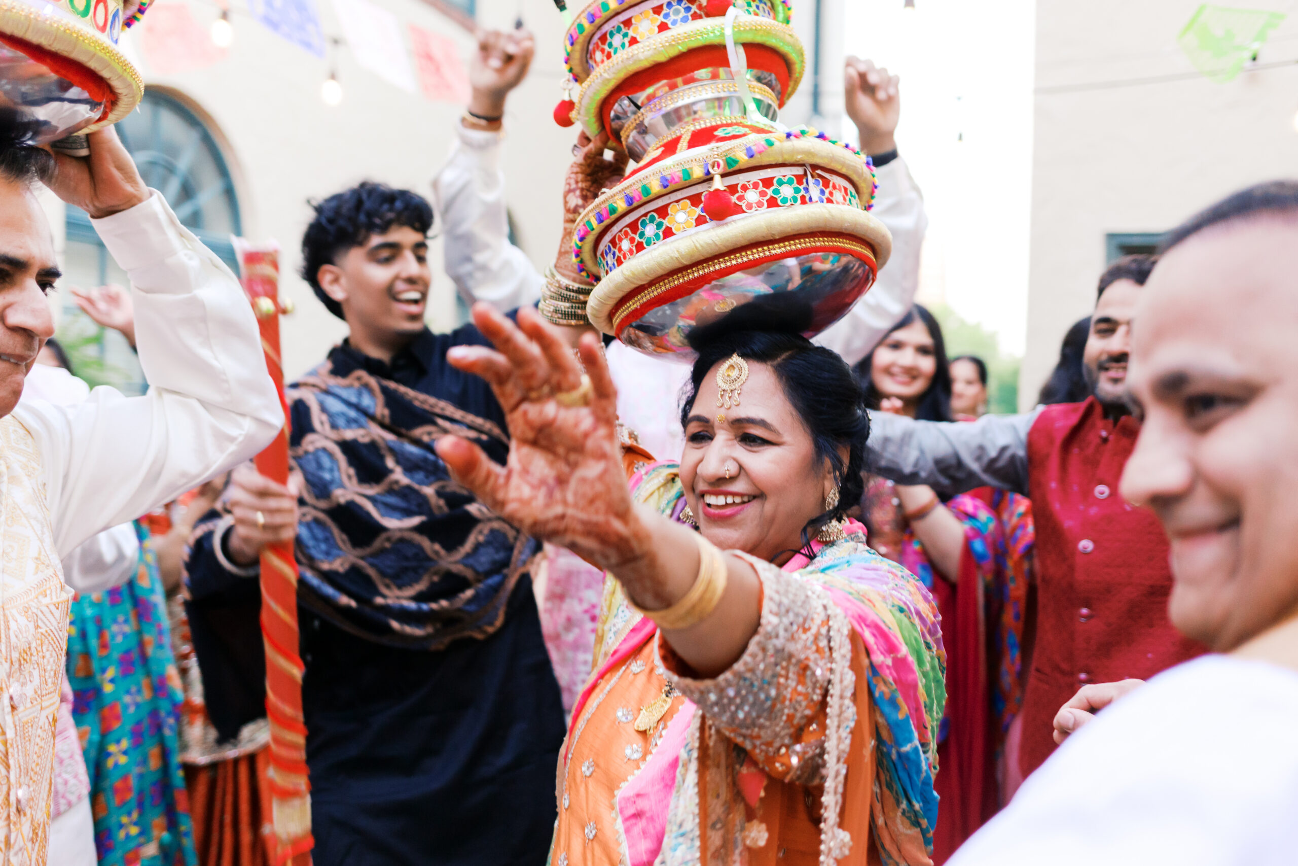 Guests dancing with decorated pots and sticks under string lights and papel picado.