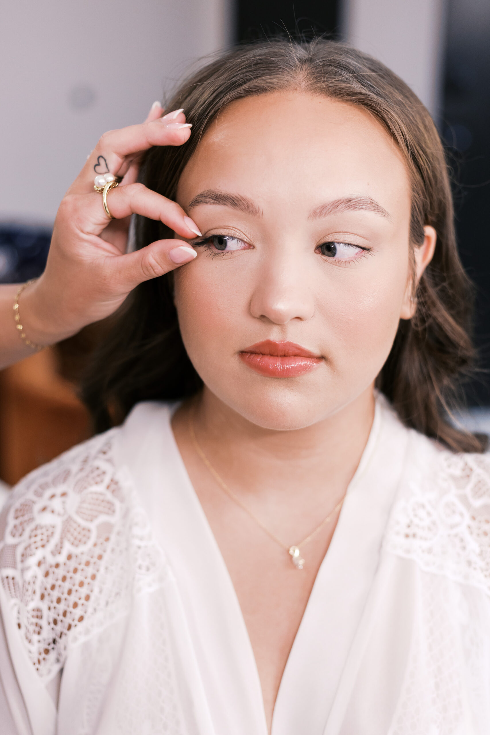 Close-up of bride’s face as false lashes are applied during wedding makeup preparation.