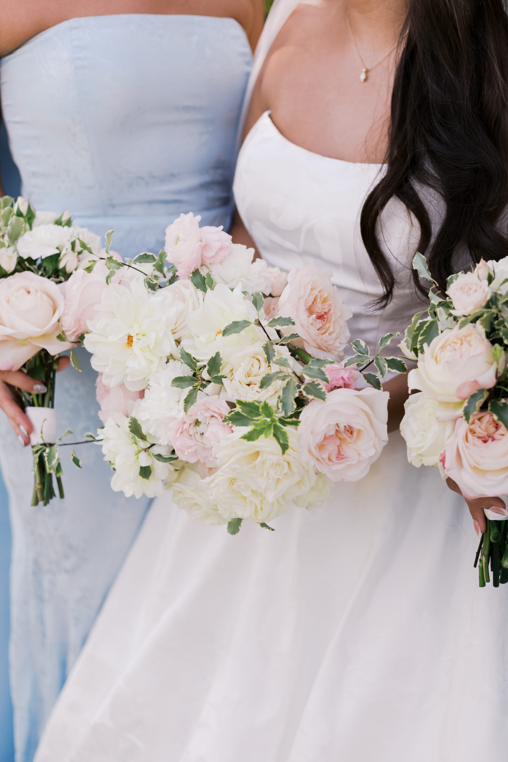 Close-up of wedding bouquets with white and blush flowers held by the bride and bridesmaids.