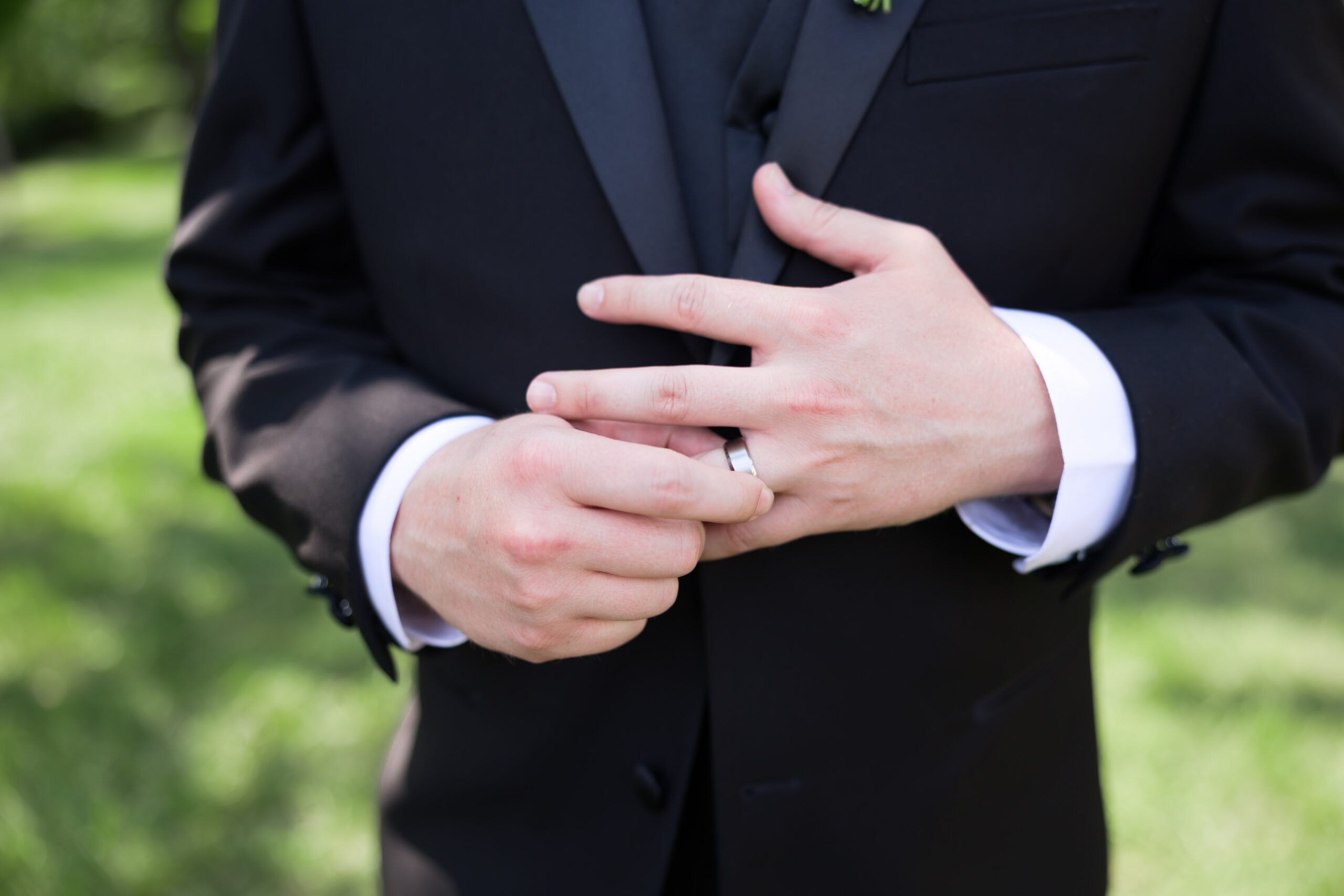 Close-up of groom's hands showing wedding ring on left hand.