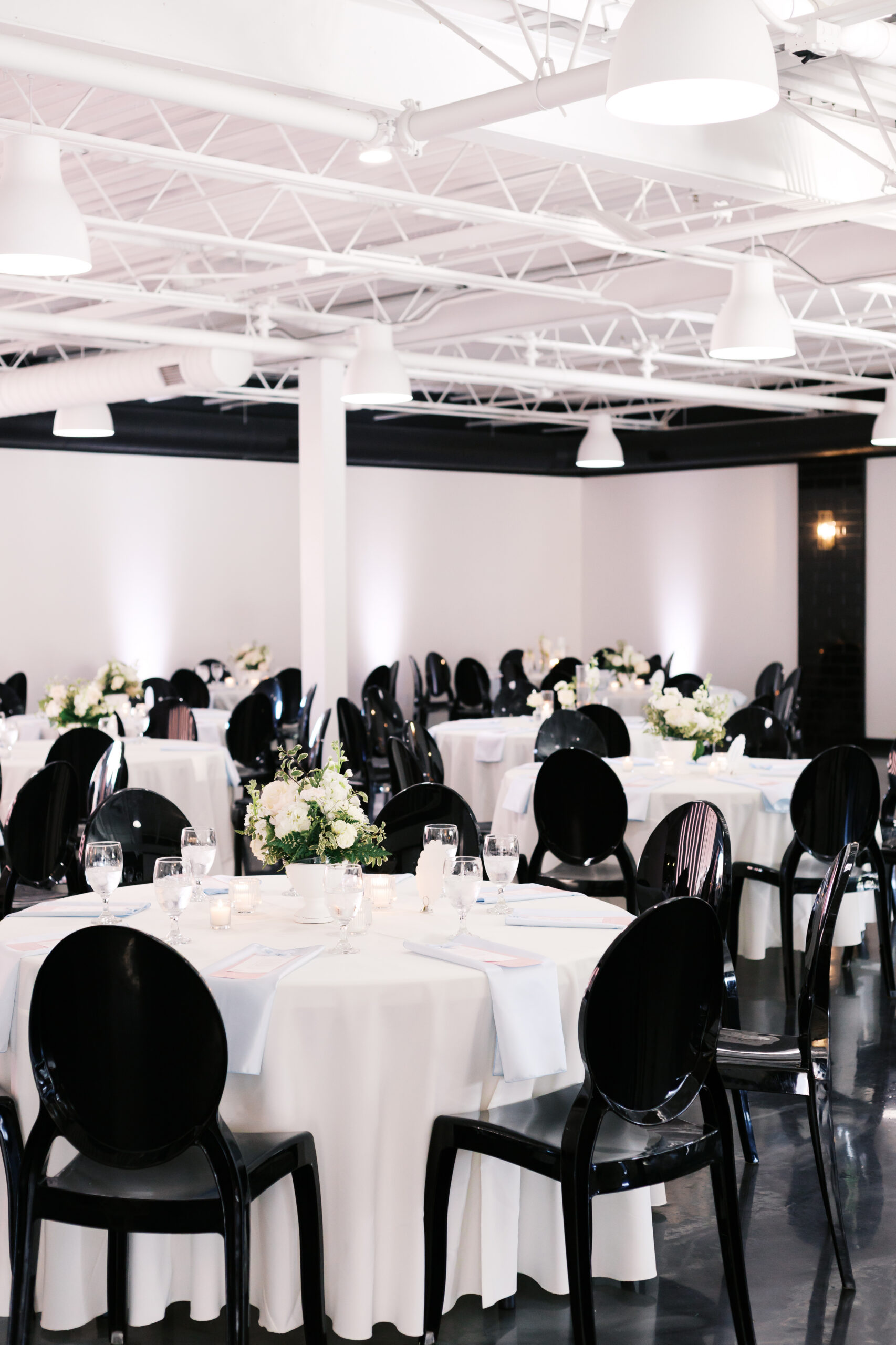 Wide view of wedding reception room with multiple round tables and head table in background.