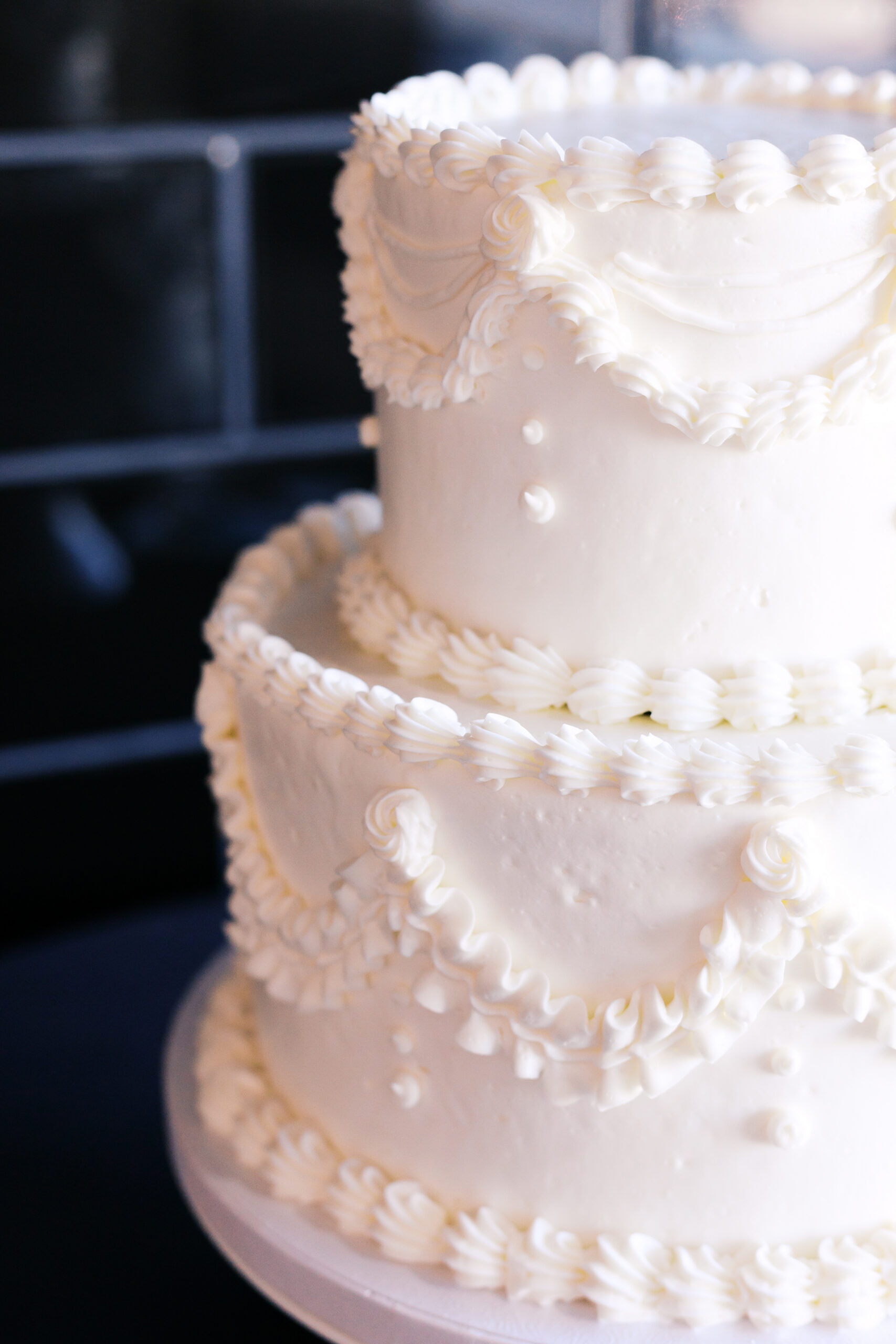 Close-up detail of white wedding cake with pearl and floral piping.