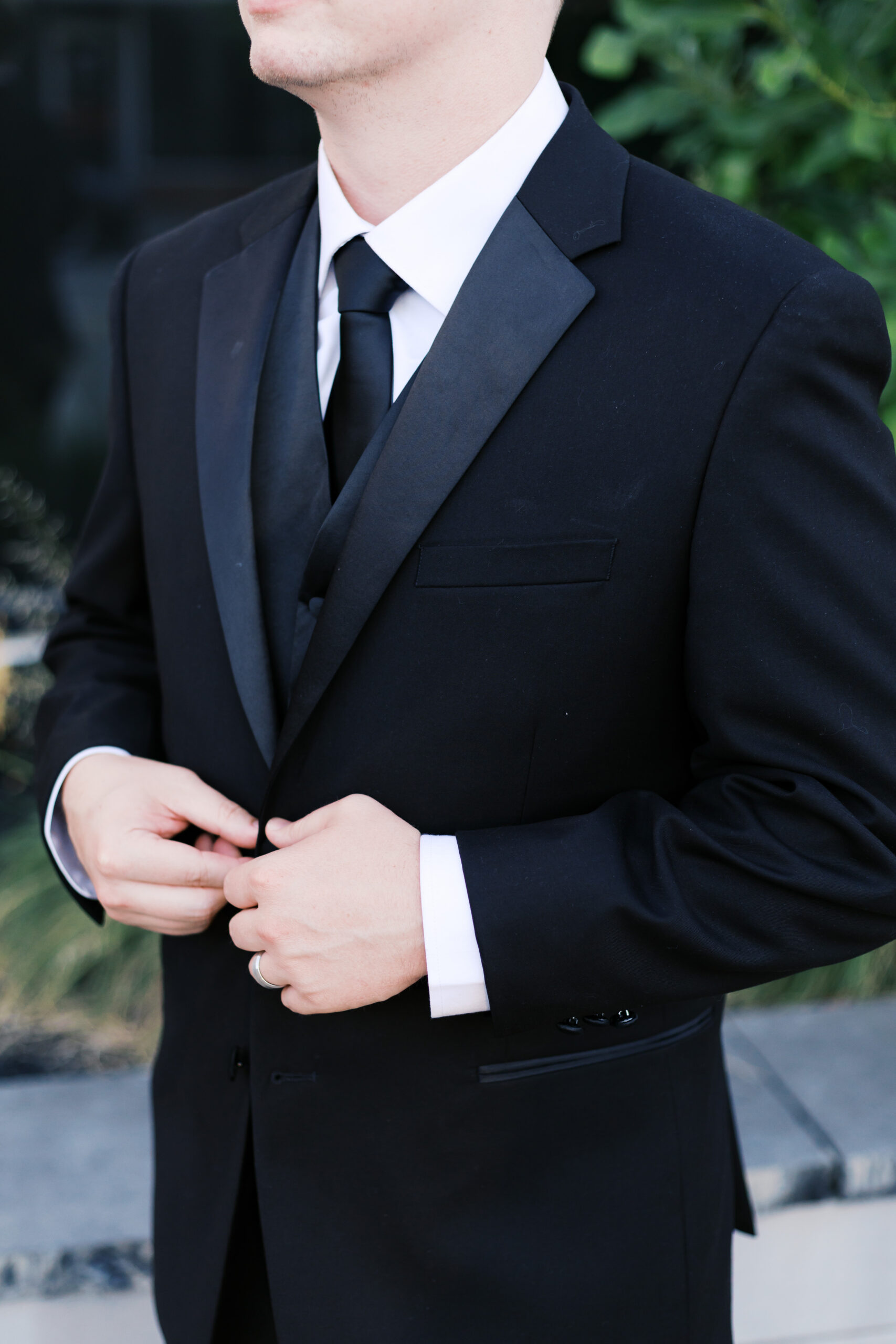Close up of the groom buttoning his suit jacket.