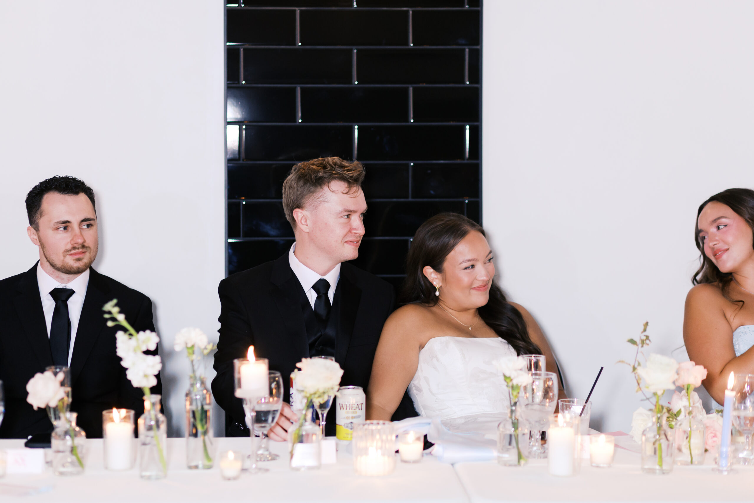 Bride leaning back on groom and smiling as they sit at the head table.