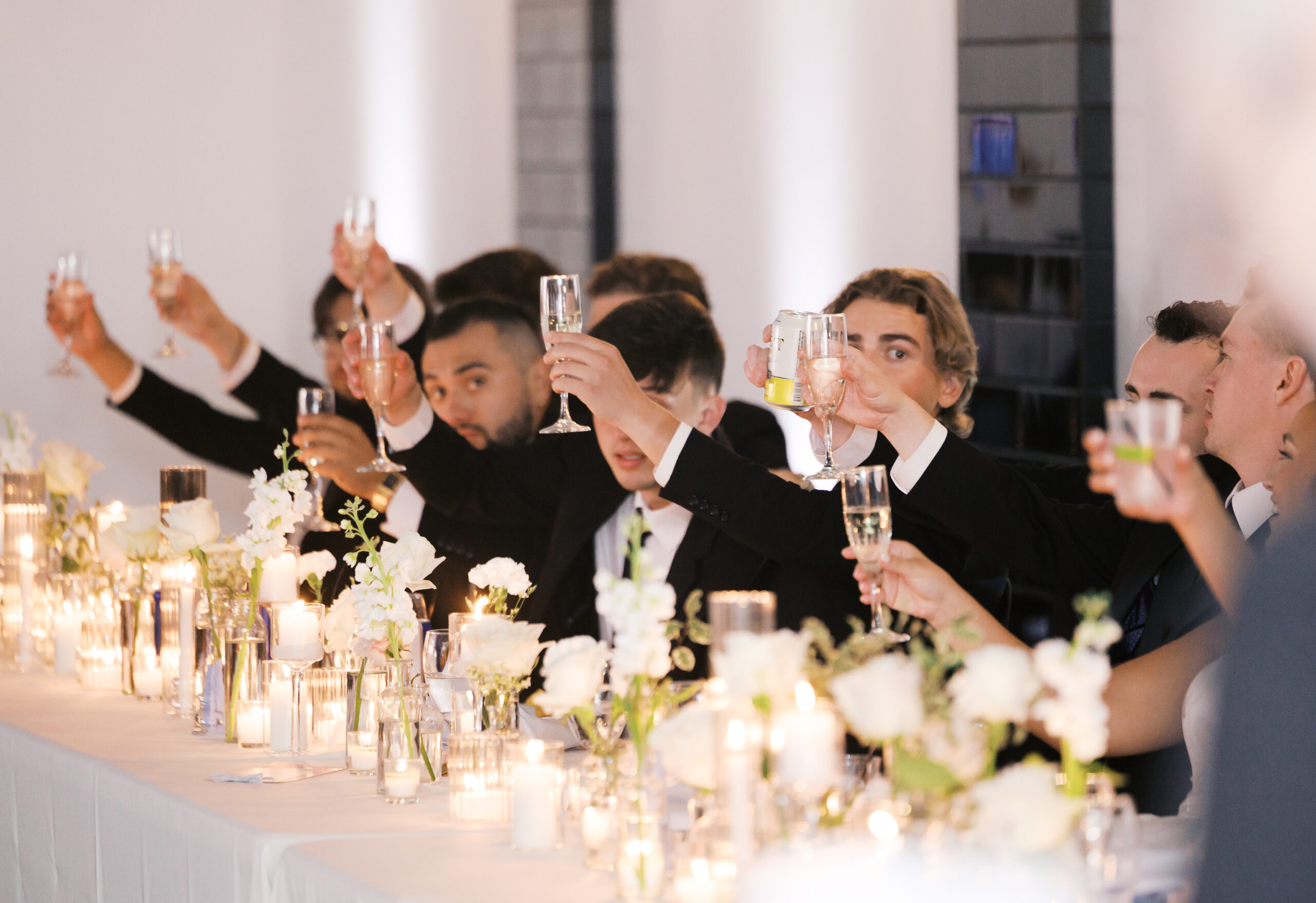 Groomsmen lifting champagne glasses in a a celebratory toast.