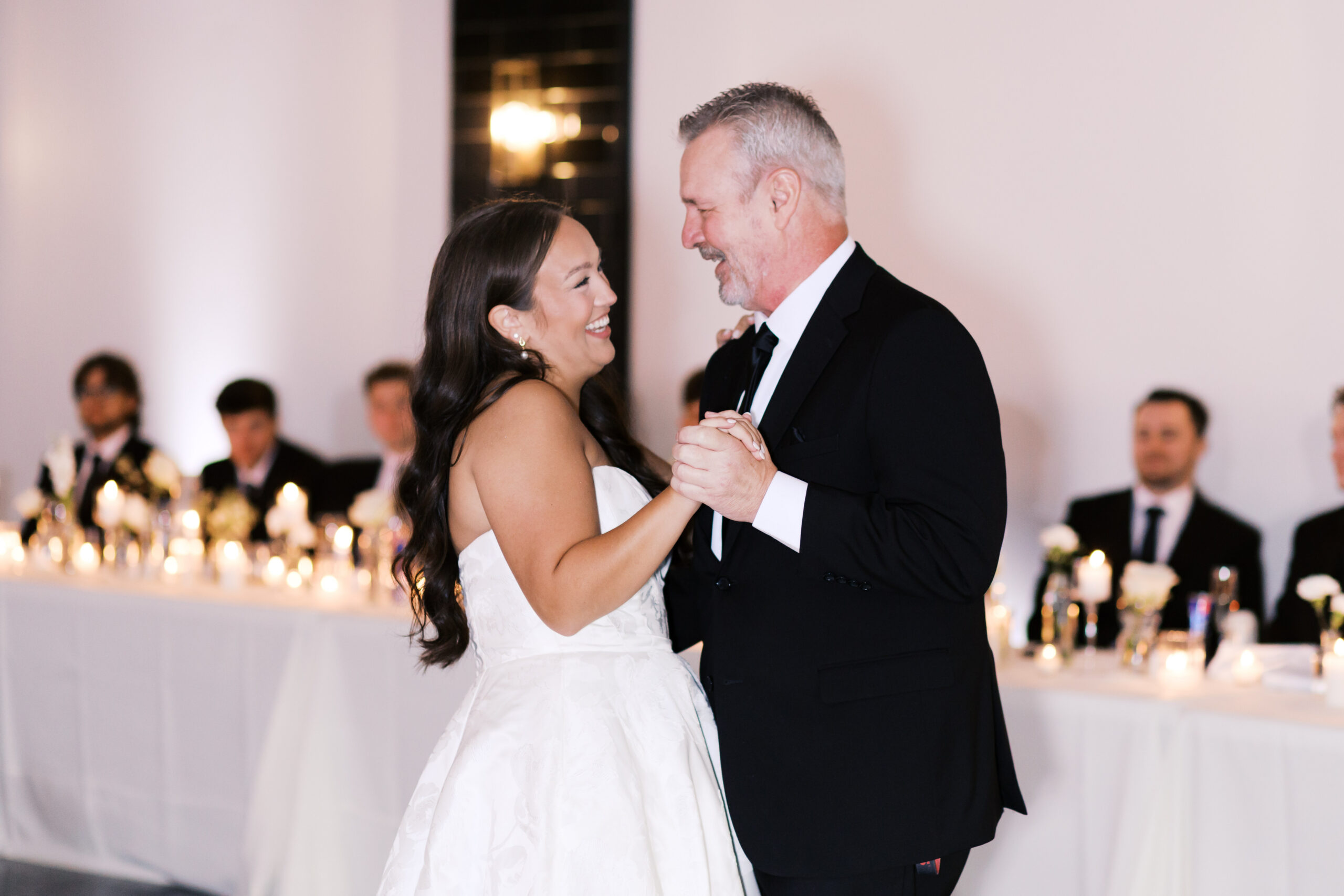 Bride smiling as she dances with her father.
