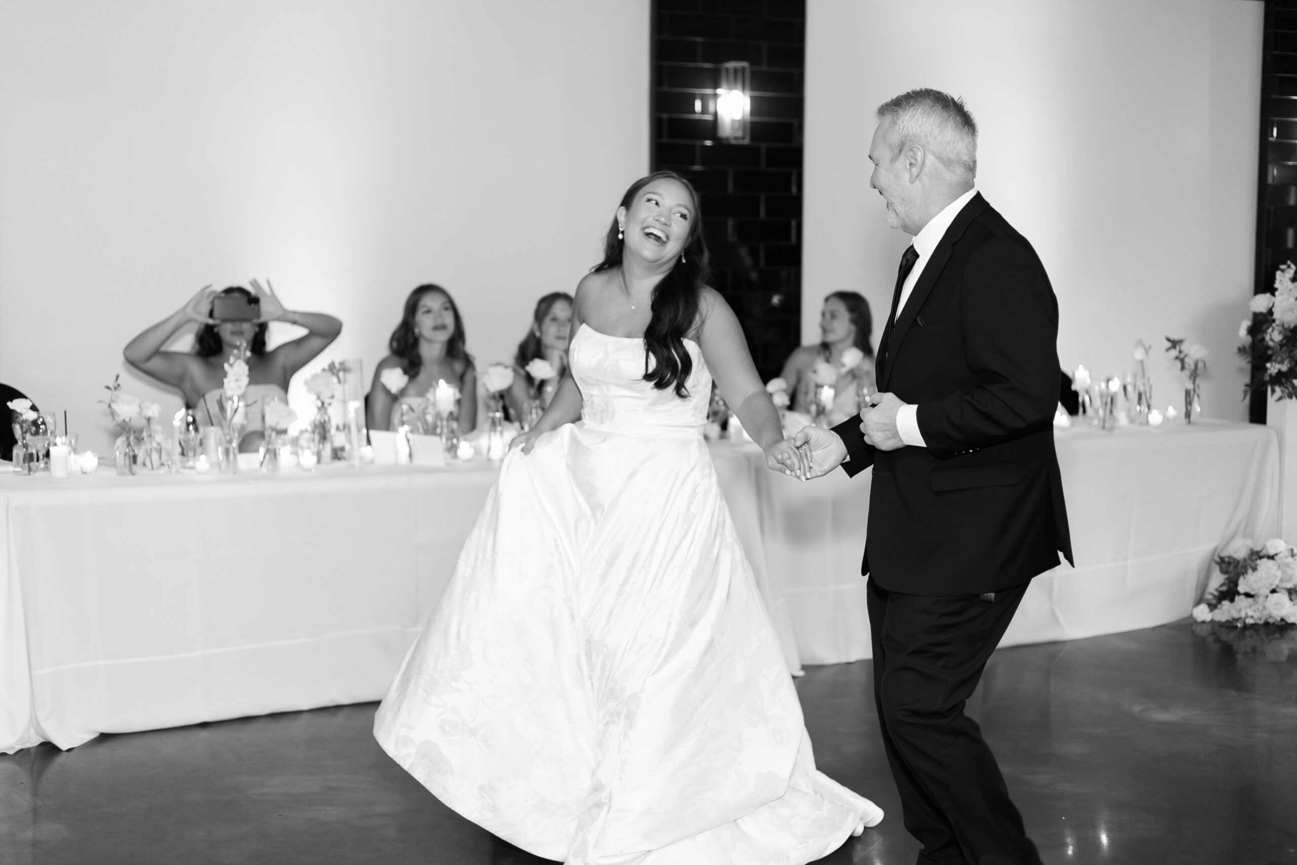 Black and white photo of the bride laughing as she dances with her dad.