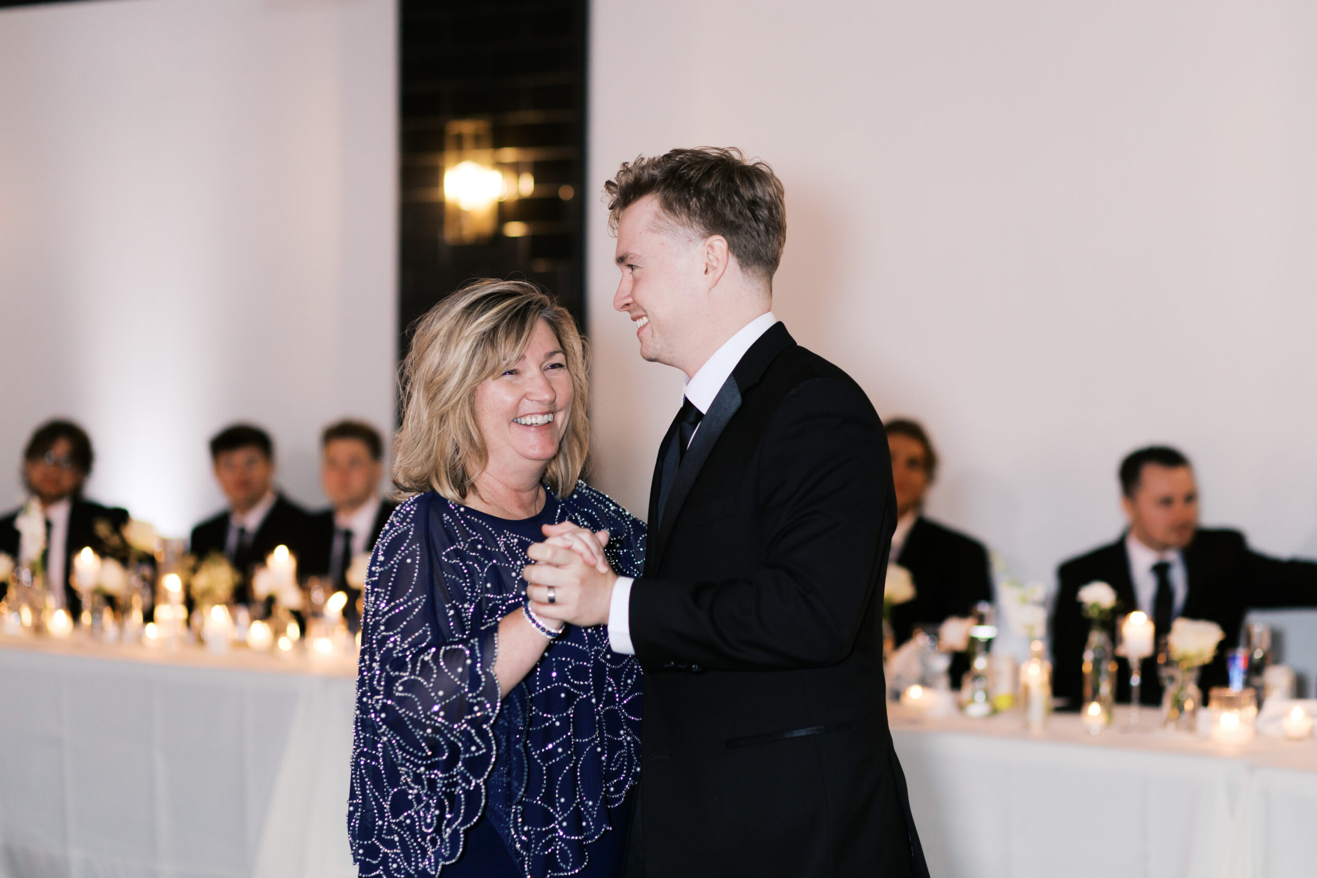 The groom dancing with his mother as they both smile.