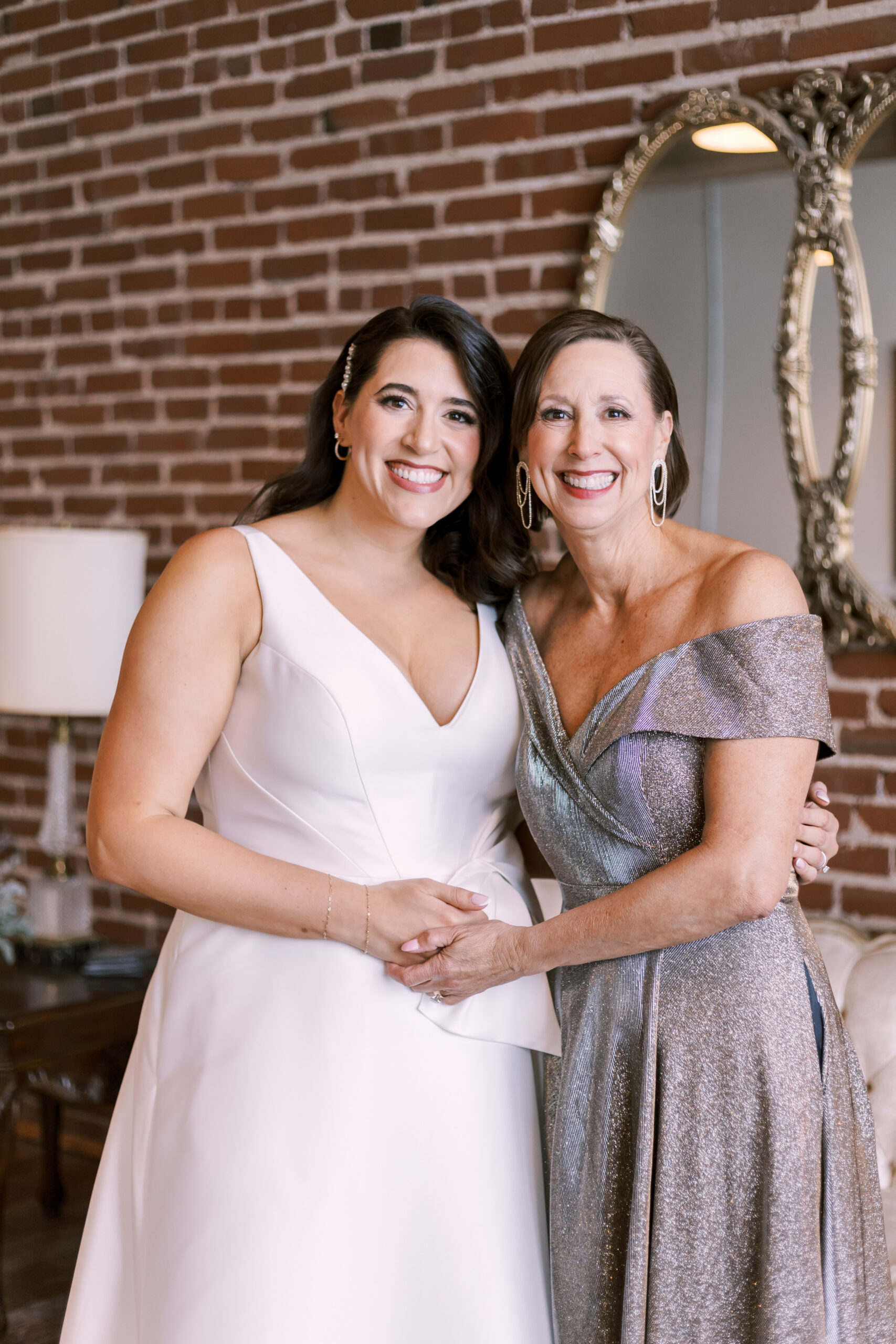 Bride in a white gown standing with an older woman in a metallic formal dress inside the Oliver Building.