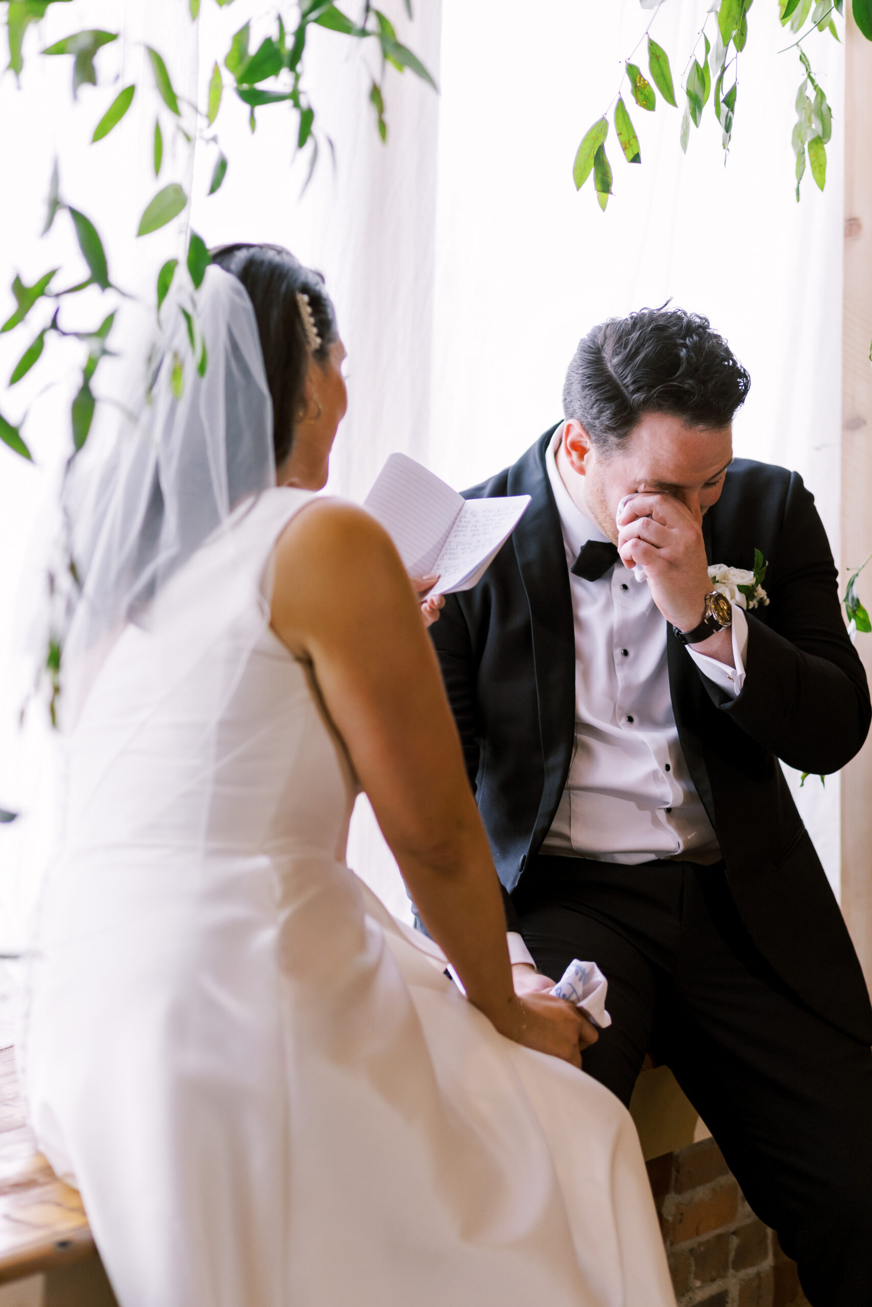 Groom wiping his eye while listening to the bride read her vows during the ceremony.