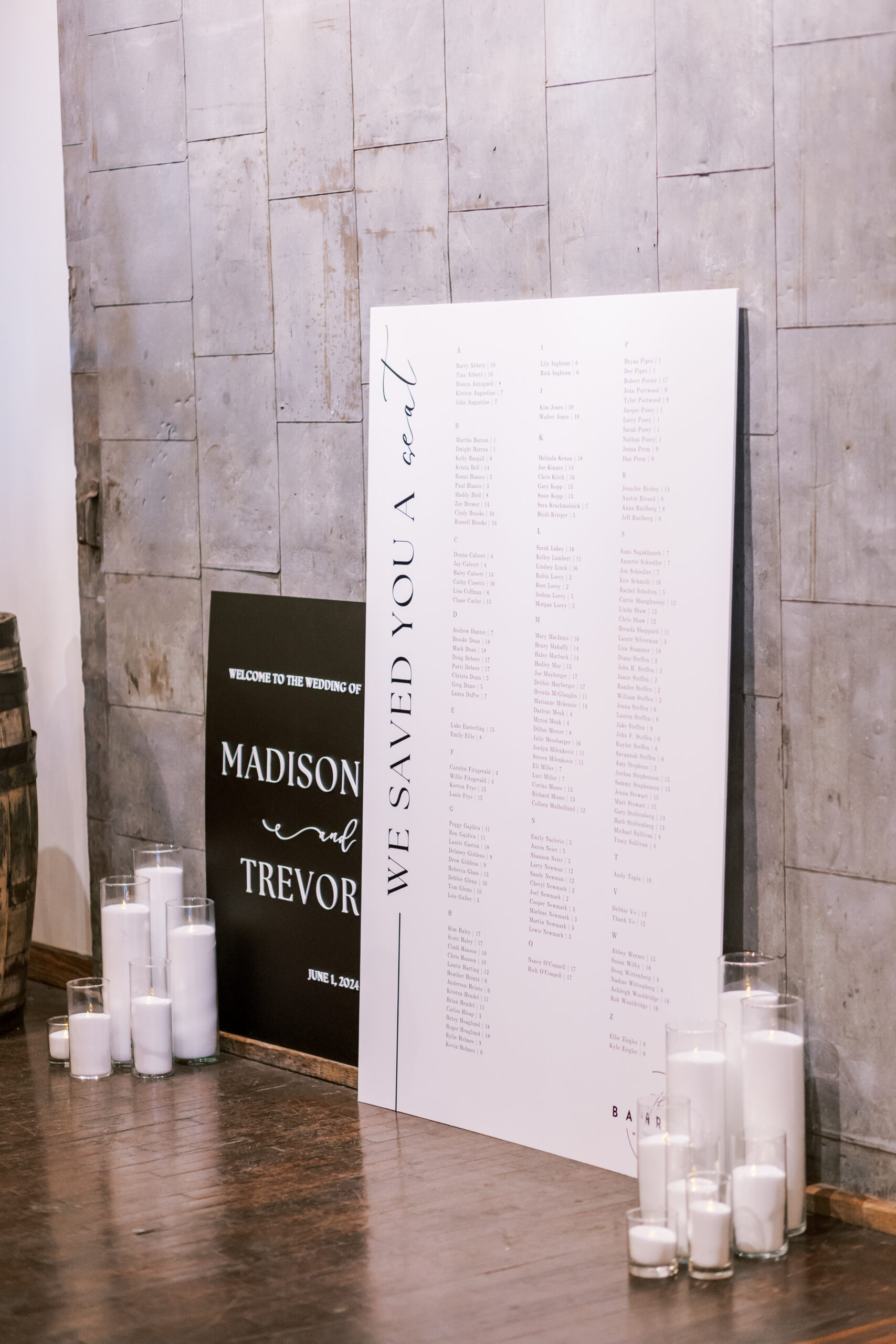 Large wedding seating chart sign displayed with candles beside a welcome sign at the reception entrance.