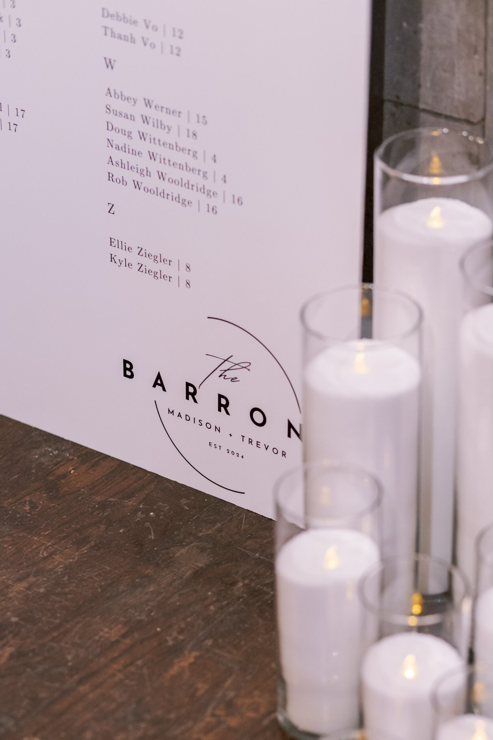 Large wedding seating chart sign displayed with candles beside a welcome sign at the reception entrance.