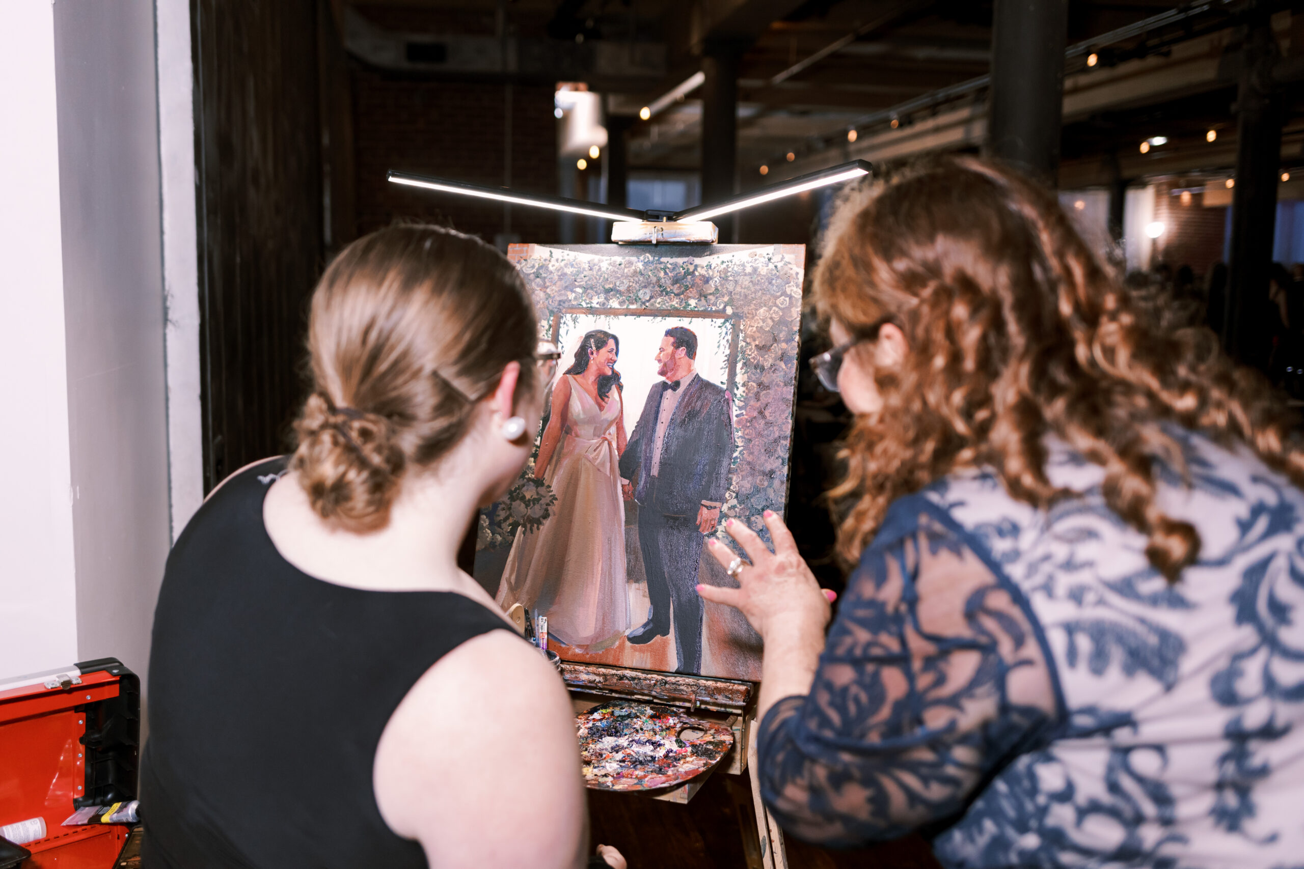 Wedding guests watching a live painter work on a portrait of the bride and groom.
